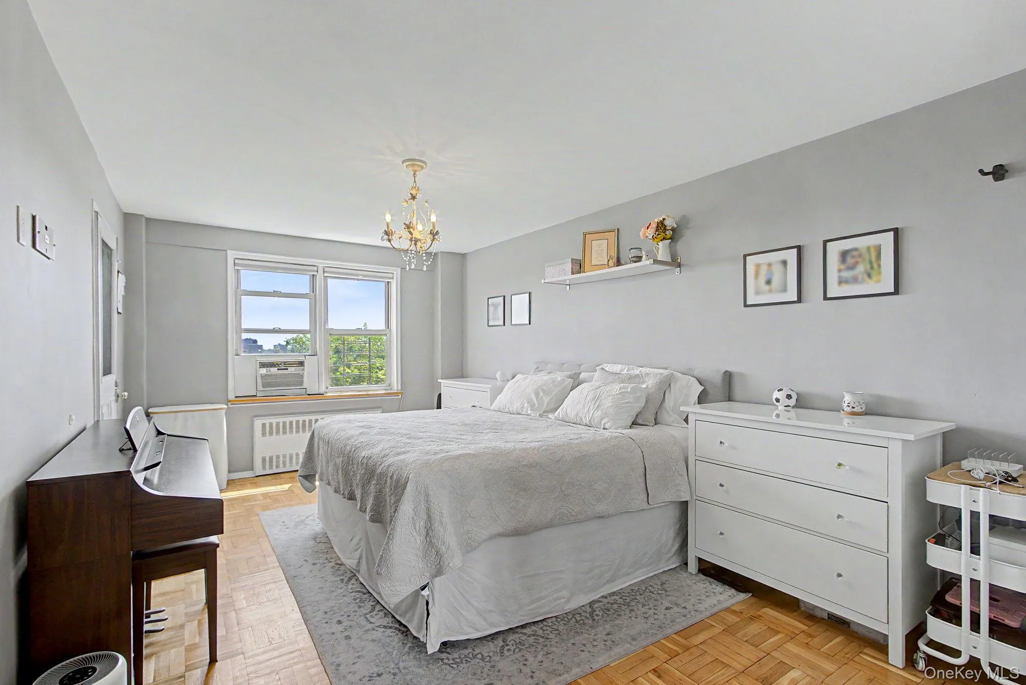 Bedroom featuring parquet wood flooring, neutral gray walls, and a chandelier light fixture Bedroom featuring parquet wood flooring, neutral gray walls, and a chandelier light fixture