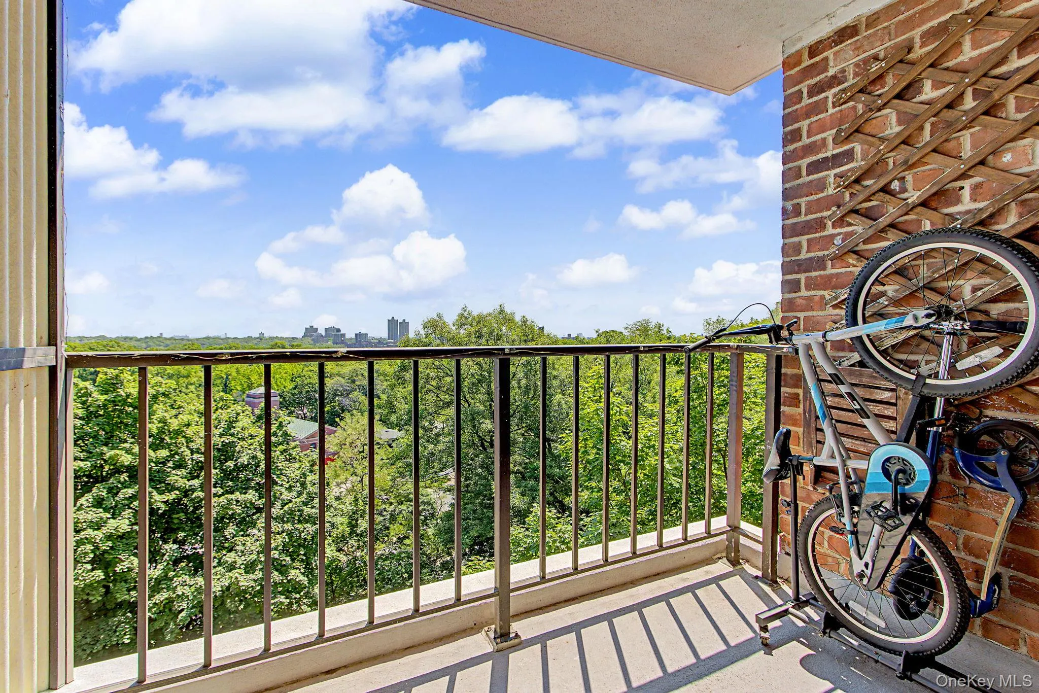Private balcony featuring a dark metal railing, concrete flooring, and a red brick exterior wall Private balcony featuring a dark metal railing, concrete flooring, and a red brick exterior wall