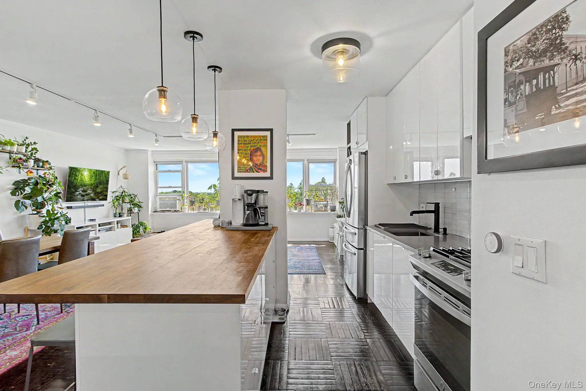 Modern kitchen featuring white high-gloss cabinetry, a black sink, and stainless steel appliances Modern kitchen featuring white high-gloss cabinetry, a black sink, and stainless steel appliances