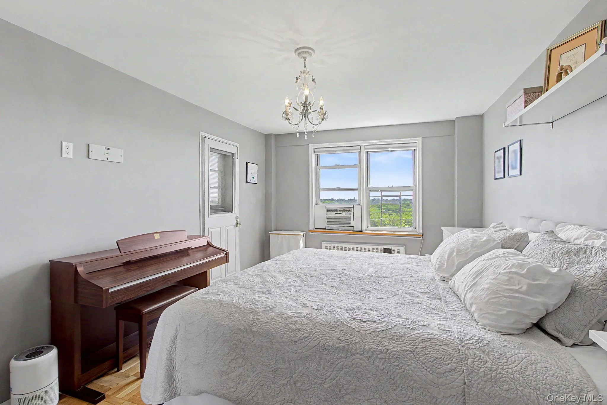 Hardwood flooring throughout featuring a window unit air conditioner, wall-mounted shelving, and a decorative ceiling fixture Hardwood flooring throughout featuring a window unit air conditioner, wall-mounted shelving, and a decorative ceiling fixture