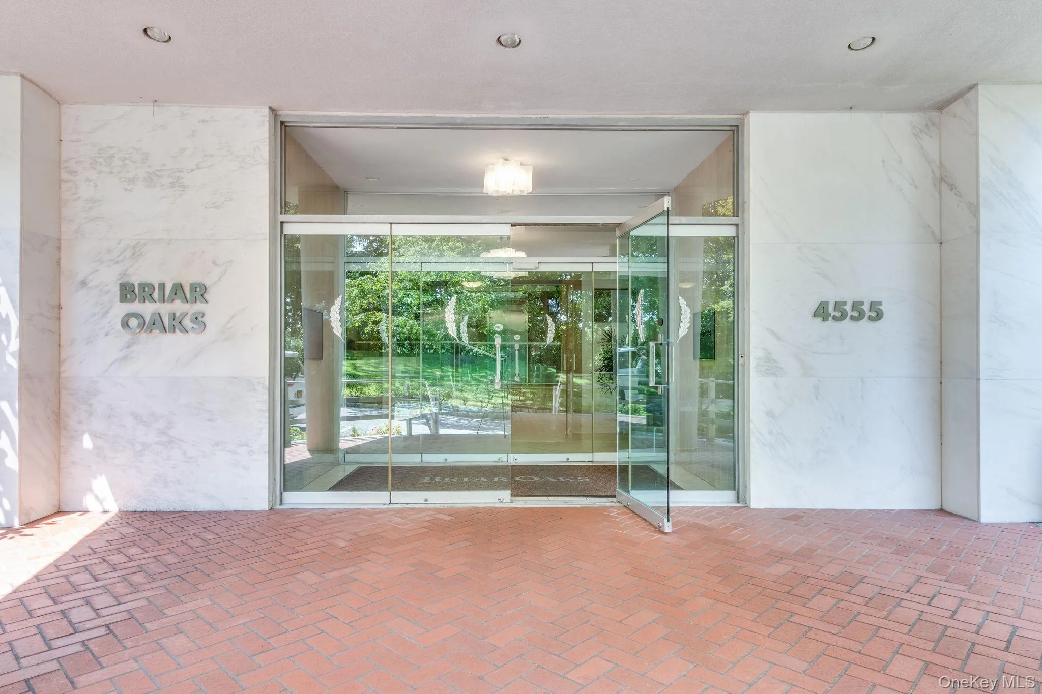 Building entrance featuring a glass door system, white marble wall cladding, and recessed ceiling lighting Building entrance featuring a glass door system, white marble wall cladding, and recessed ceiling lighting