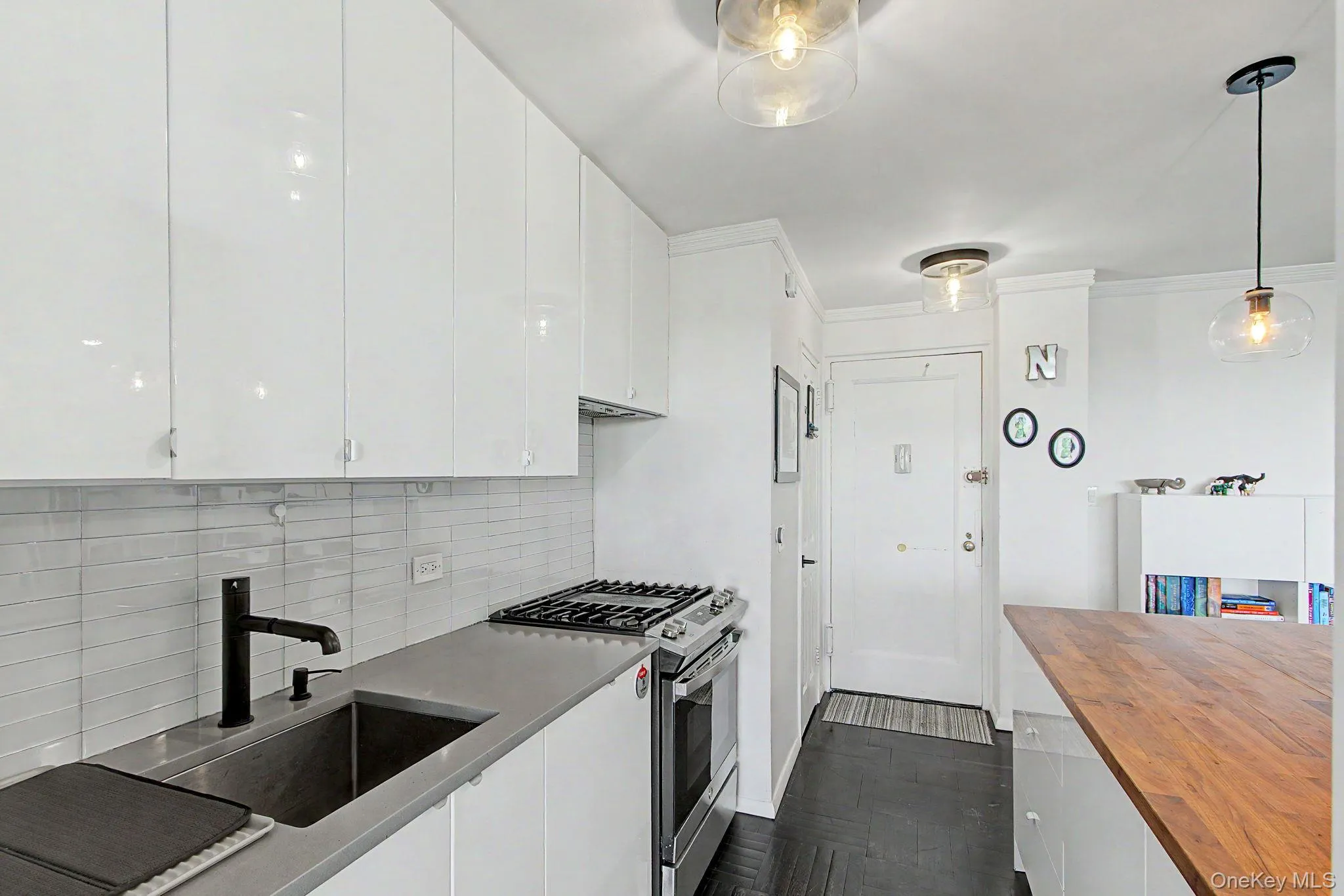 Contemporary kitchen featuring flat-panel white cabinetry, a stainless steel gas range, and a sleek undermount sink with a matte black faucet Contemporary kitchen featuring flat-panel white cabinetry, a stainless steel gas range, and a sleek undermount sink with a matte black faucet