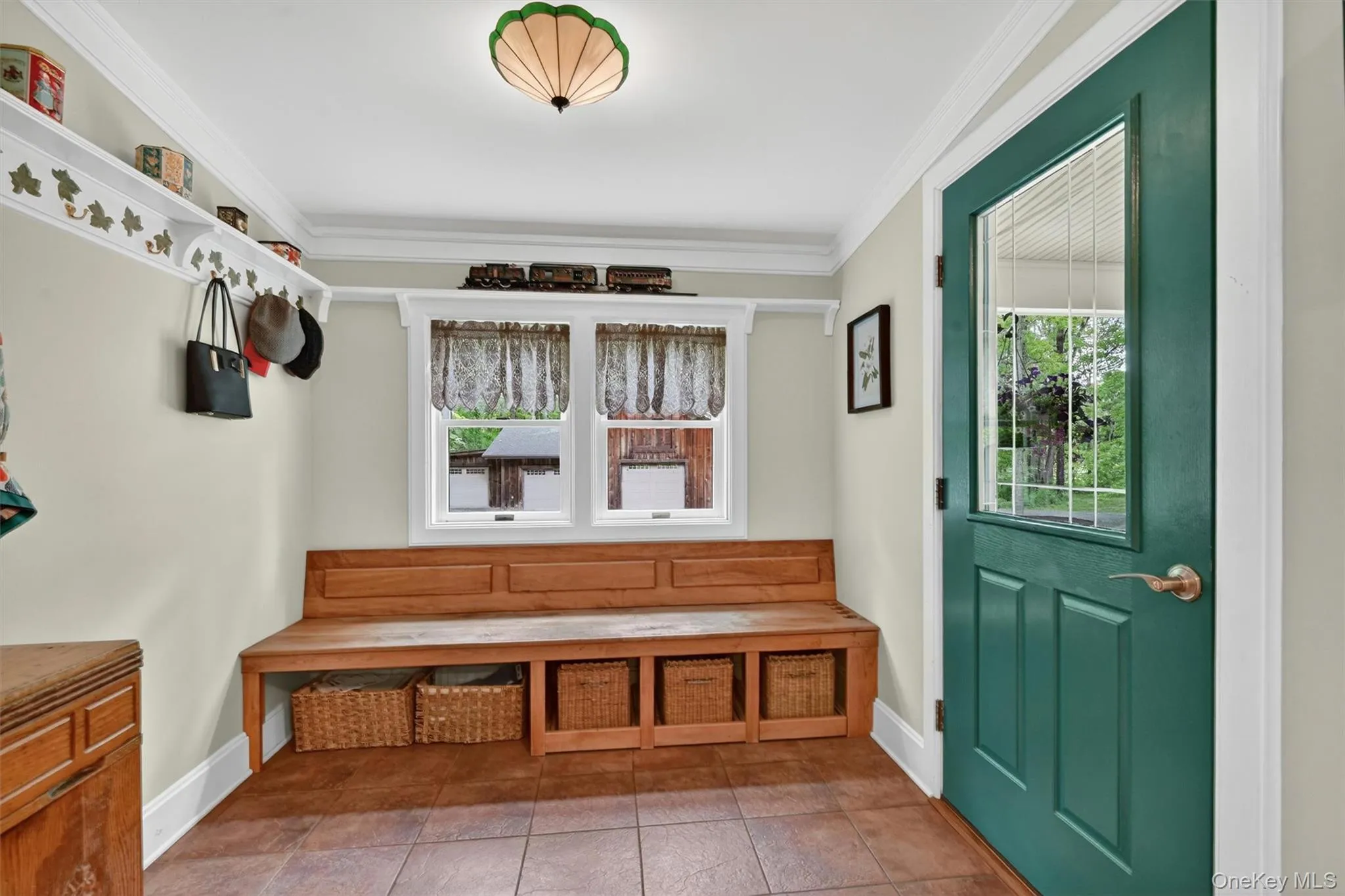 Entryway featuring a built-in wooden bench with storage, two windows, and a green door with a glass panel Entryway featuring a built-in wooden bench with storage, two windows, and a green door with a glass panel