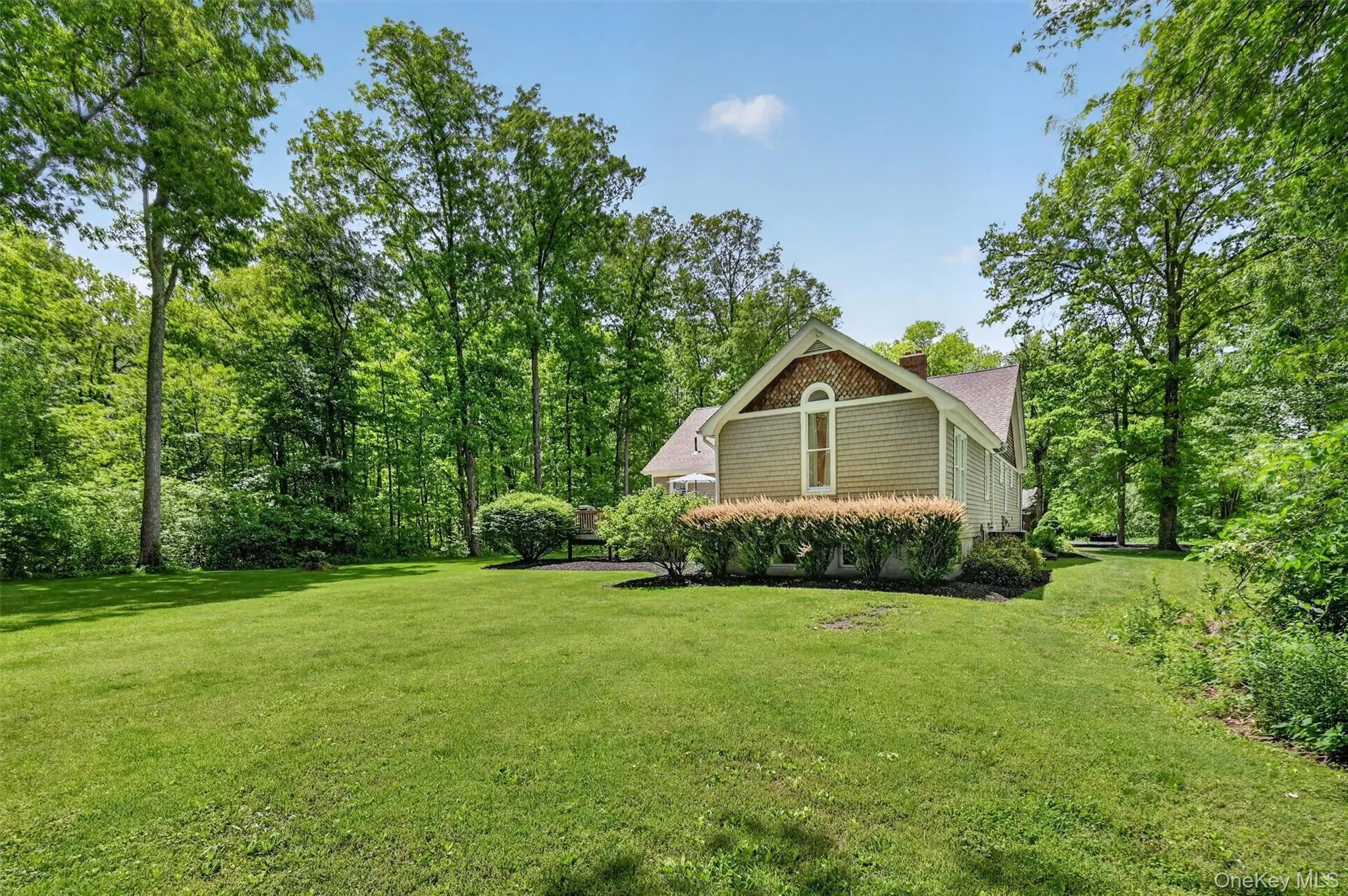 Expansive lawn bordered by mature trees, offering a peaceful and private outdoor setting with well-kept landscaping surrounding the home Expansive lawn bordered by mature trees, offering a peaceful and private outdoor setting with well-kept landscaping surrounding the home