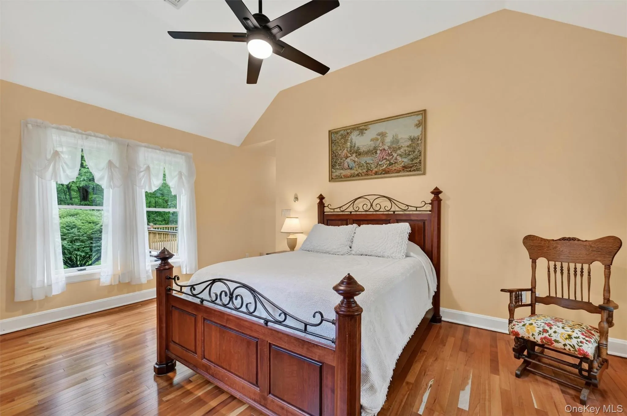 Vaulted ceiling bedroom with light-toned wall paint and hardwood flooring Vaulted ceiling bedroom with light-toned wall paint and hardwood flooring