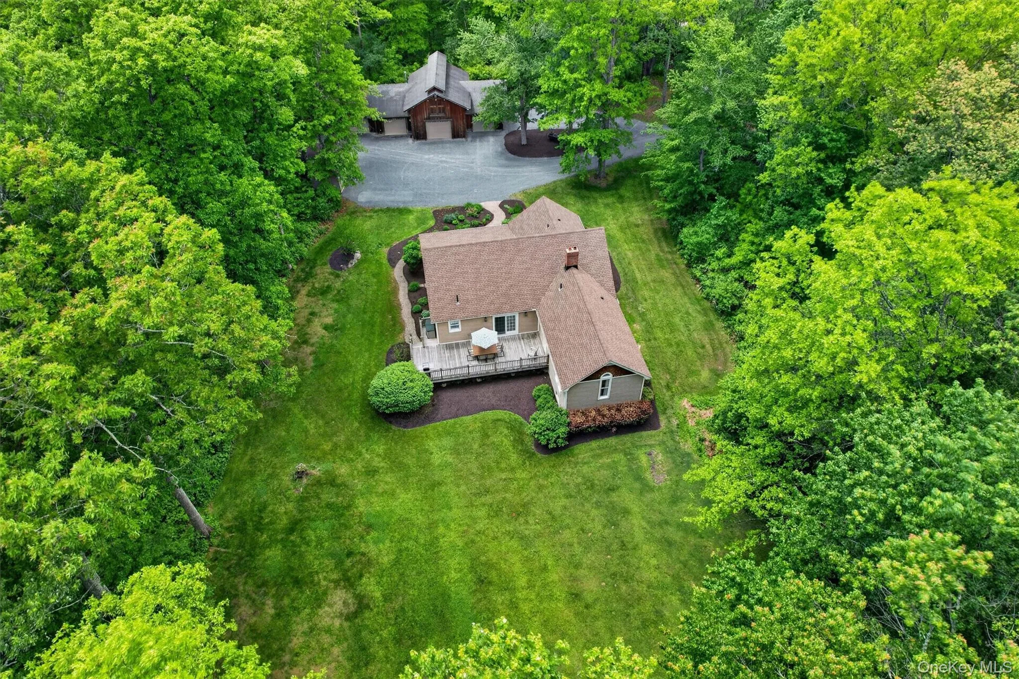 Expansive property featuring a residence with a light brown shingle roof, surrounded by mature trees Expansive property featuring a residence with a light brown shingle roof, surrounded by mature trees