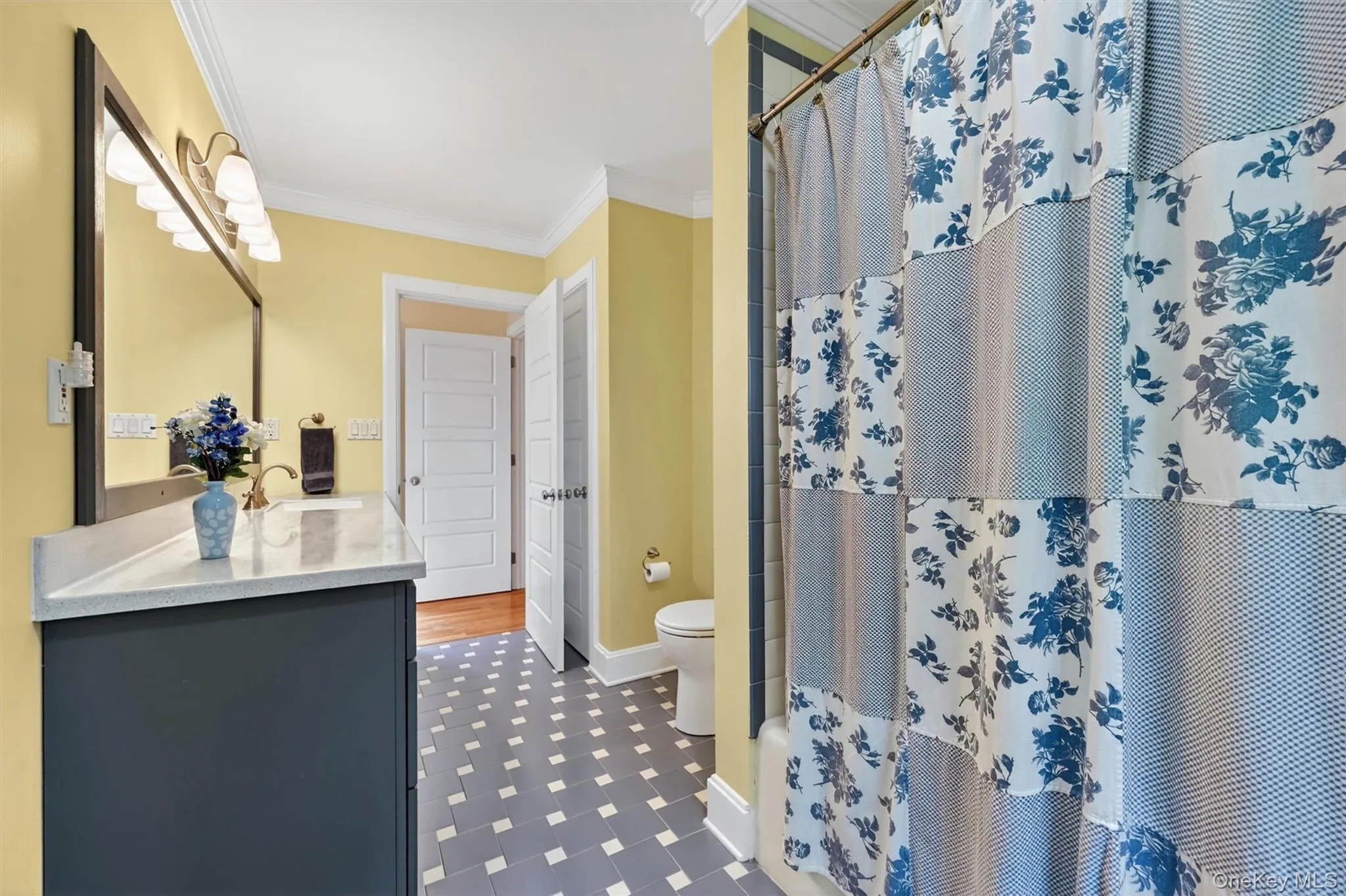 Bathroom featuring a single vanity with a light-toned countertop, a large framed mirror, and a wall-mounted light fixture Bathroom featuring a single vanity with a light-toned countertop, a large framed mirror, and a wall-mounted light fixture