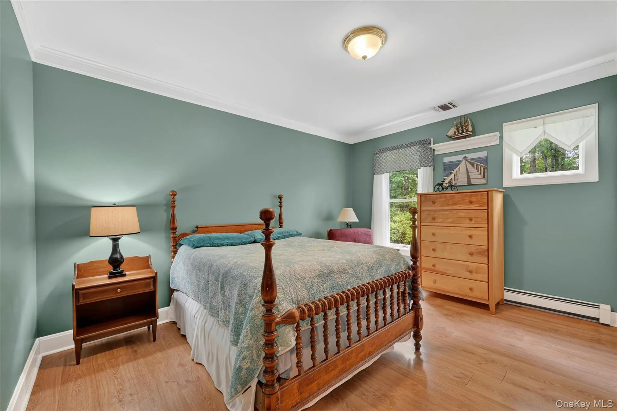 Bedroom featuring wood-finish flooring, two windows with white trim, and crown molding Bedroom featuring wood-finish flooring, two windows with white trim, and crown molding