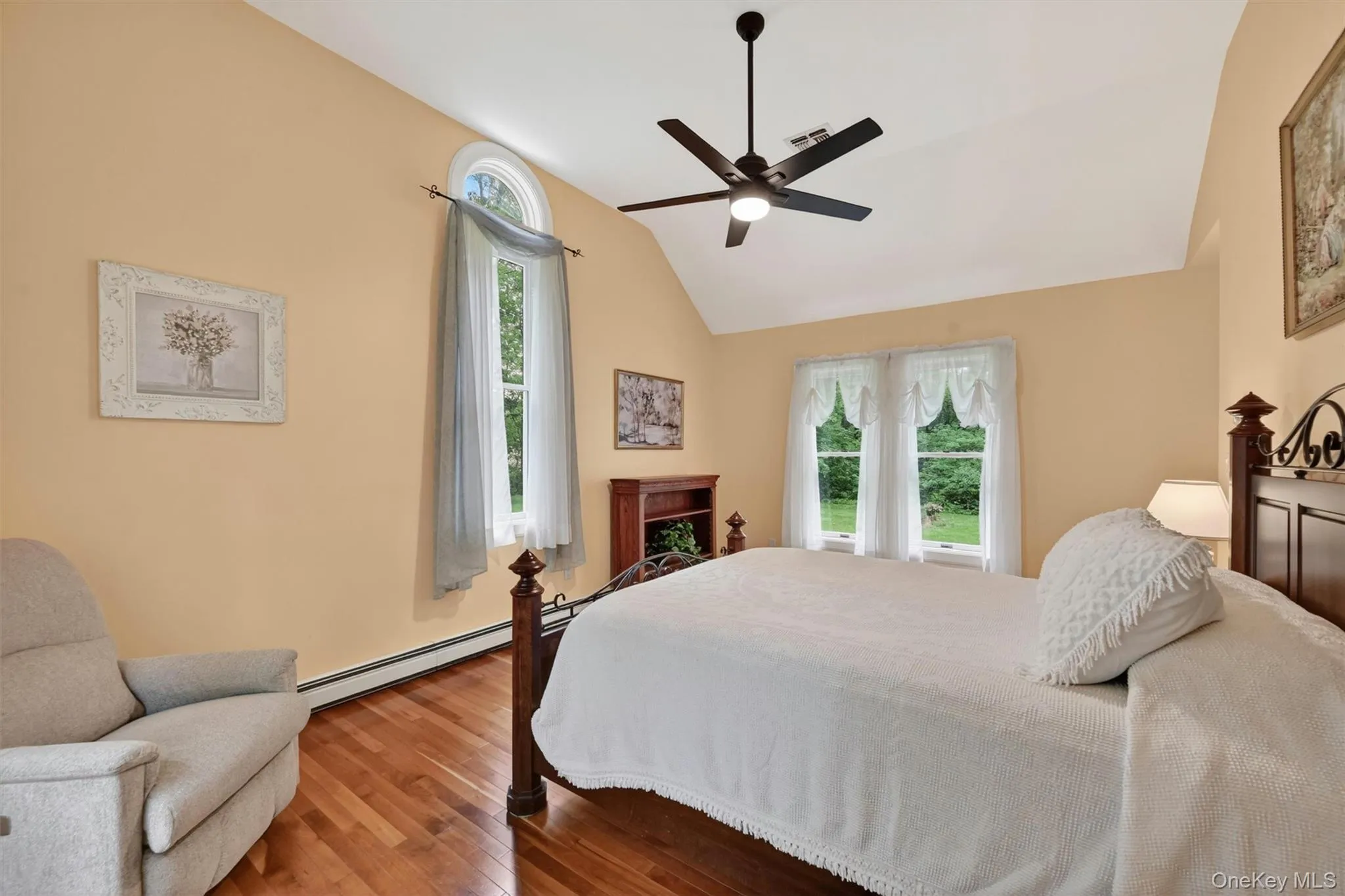 Vaulted ceiling featuring a black ceiling fan, hardwood flooring, and multiple windows including an arched transom window Vaulted ceiling featuring a black ceiling fan, hardwood flooring, and multiple windows including an arched transom window