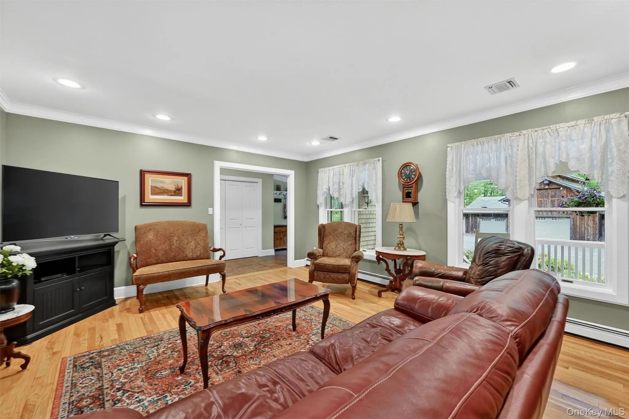 Spacious living area featuring wood-finish flooring, recessed lighting, and crown molding Spacious living area featuring wood-finish flooring, recessed lighting, and crown molding