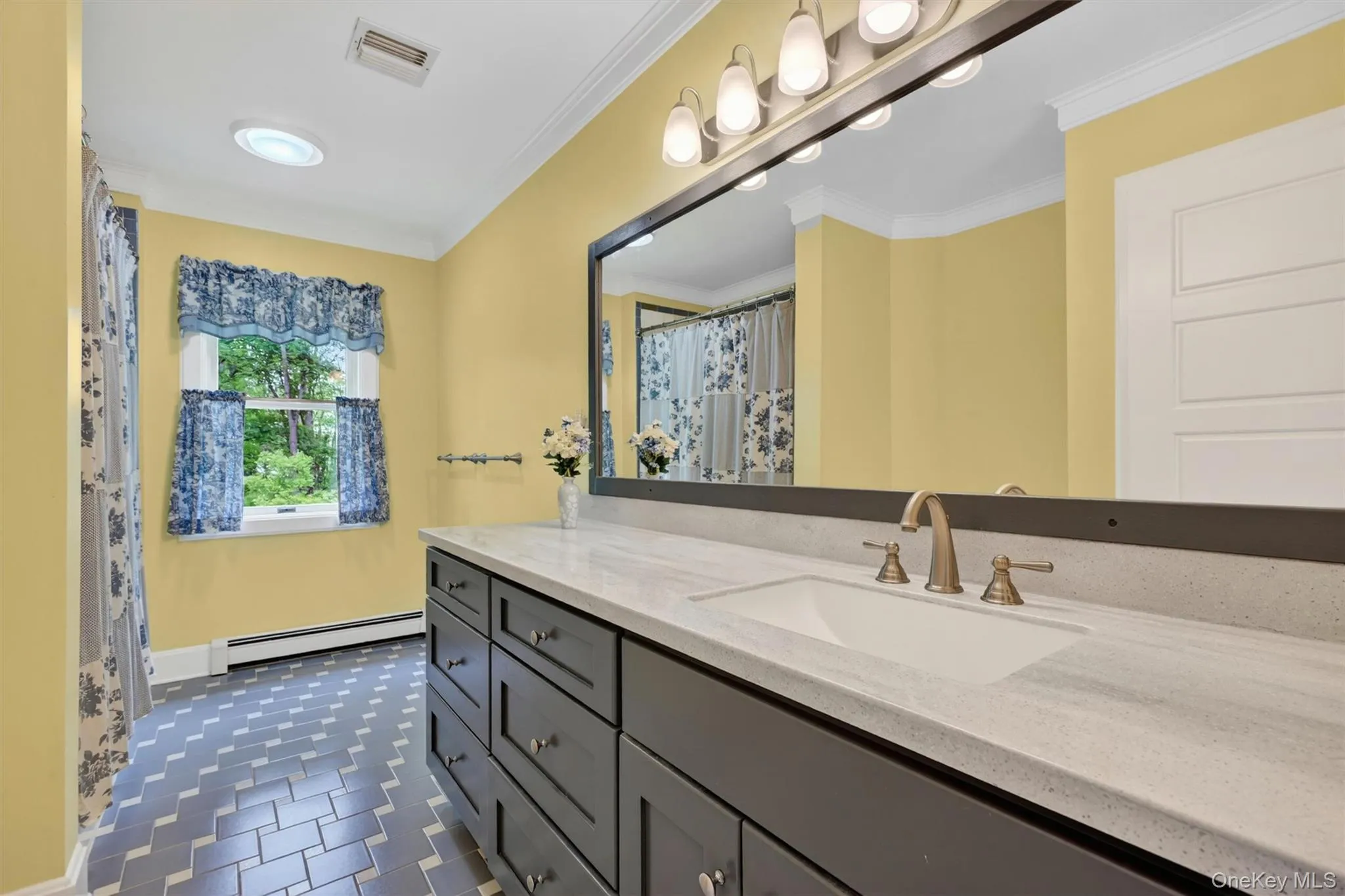 Dual-sink vanity with a light-toned countertop and brushed bronze fixtures Dual-sink vanity with a light-toned countertop and brushed bronze fixtures
