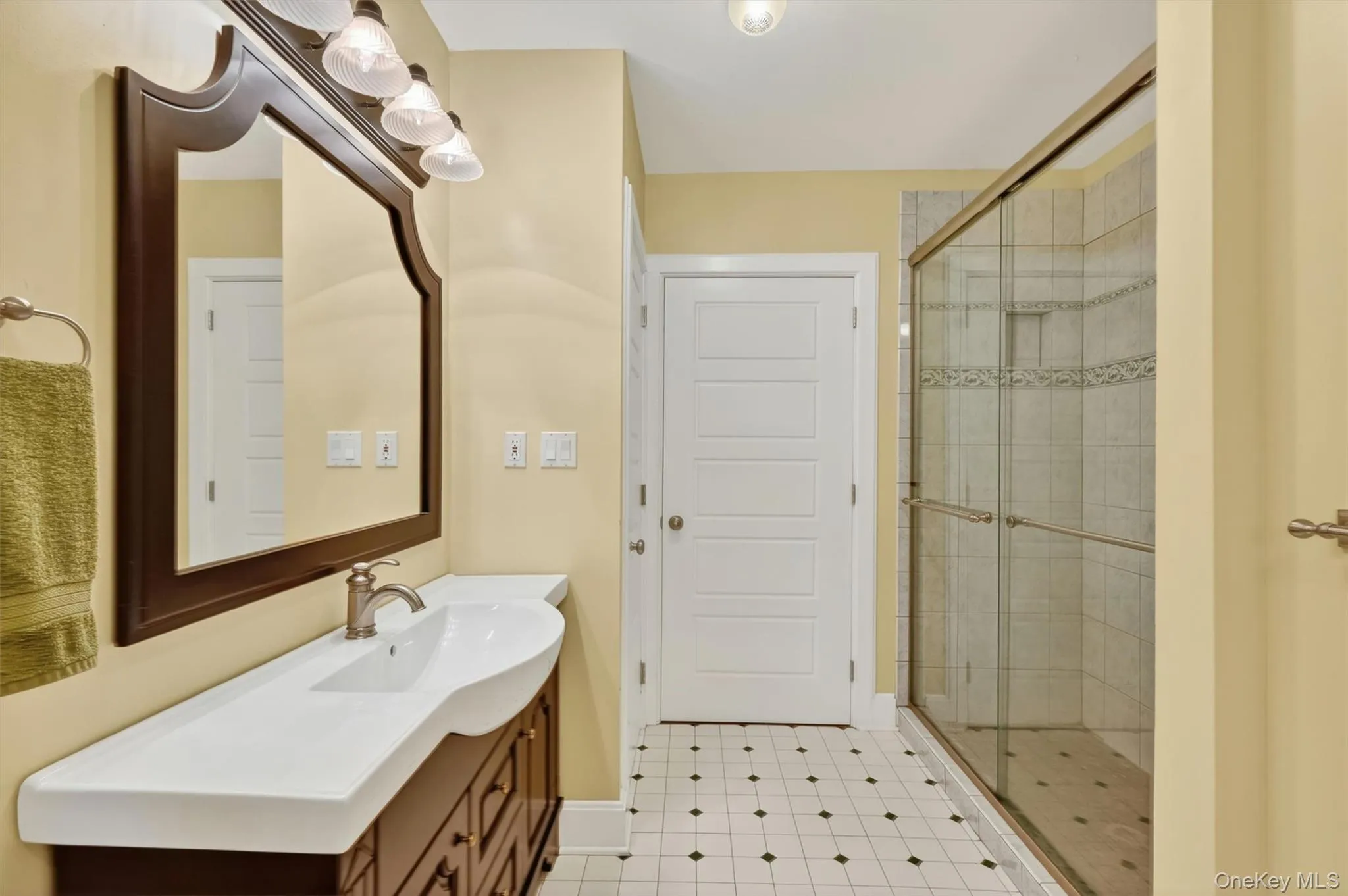 Bathroom featuring a dark wood vanity with an integrated white sink, a framed mirror, and a clear glass shower enclosure Bathroom featuring a dark wood vanity with an integrated white sink, a framed mirror, and a clear glass shower enclosure