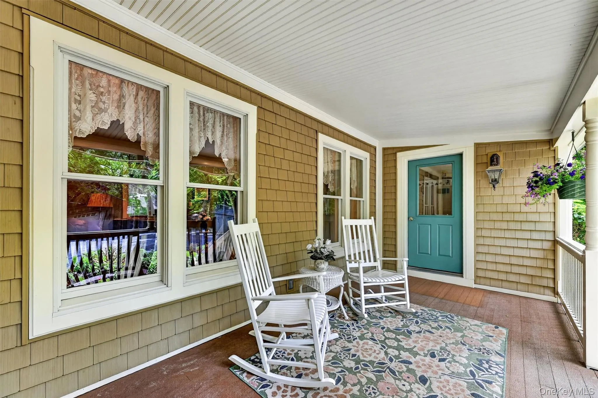 A charming covered front porch with warm shingle siding, crisp white trim, and a welcoming teal front door A charming covered front porch with warm shingle siding, crisp white trim, and a welcoming teal front door