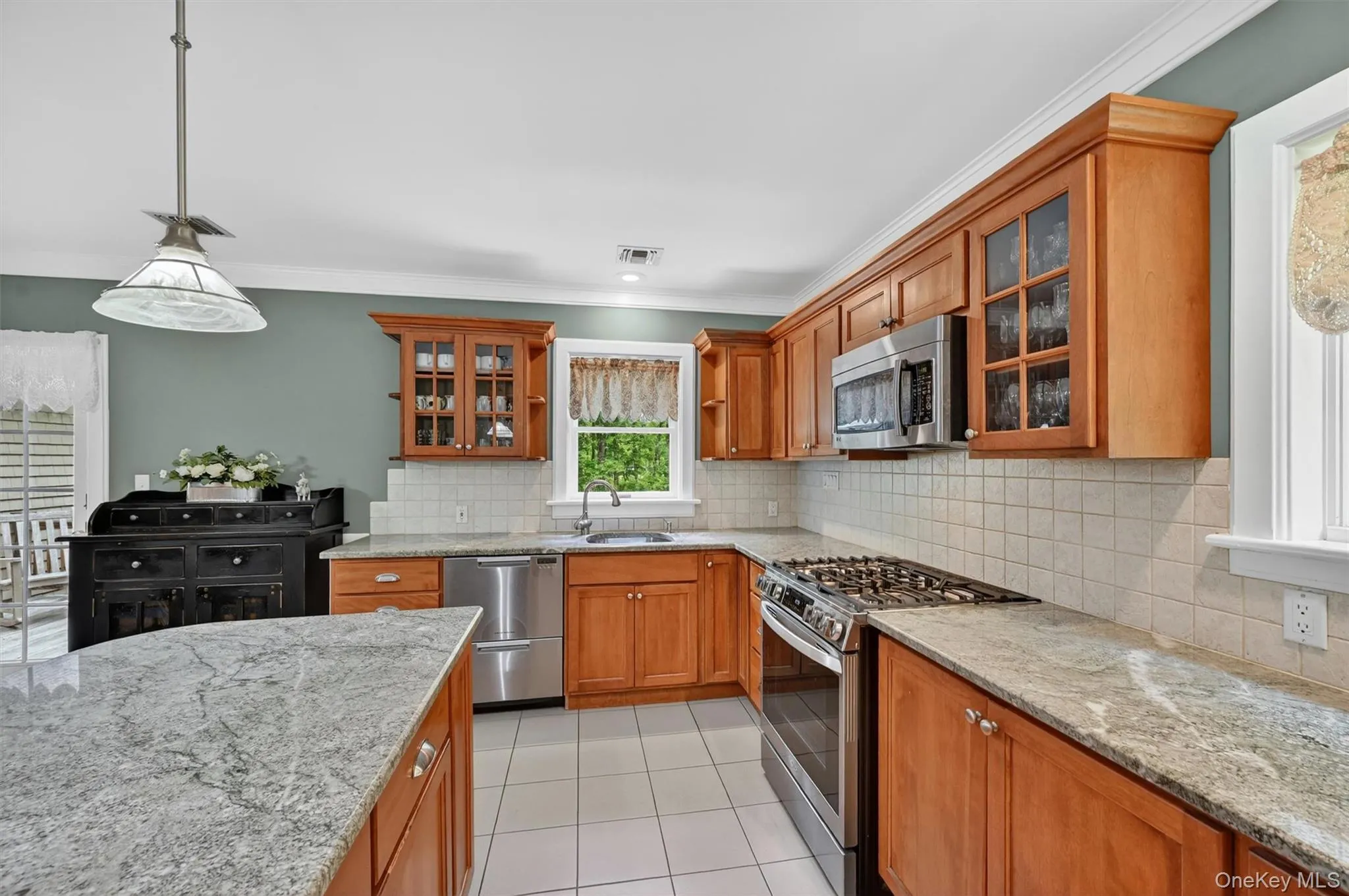 Kitchen with light wood cabinetry, granite-style countertops, stainless steel appliances, and white tile flooring Kitchen with light wood cabinetry, granite-style countertops, stainless steel appliances, and white tile flooring