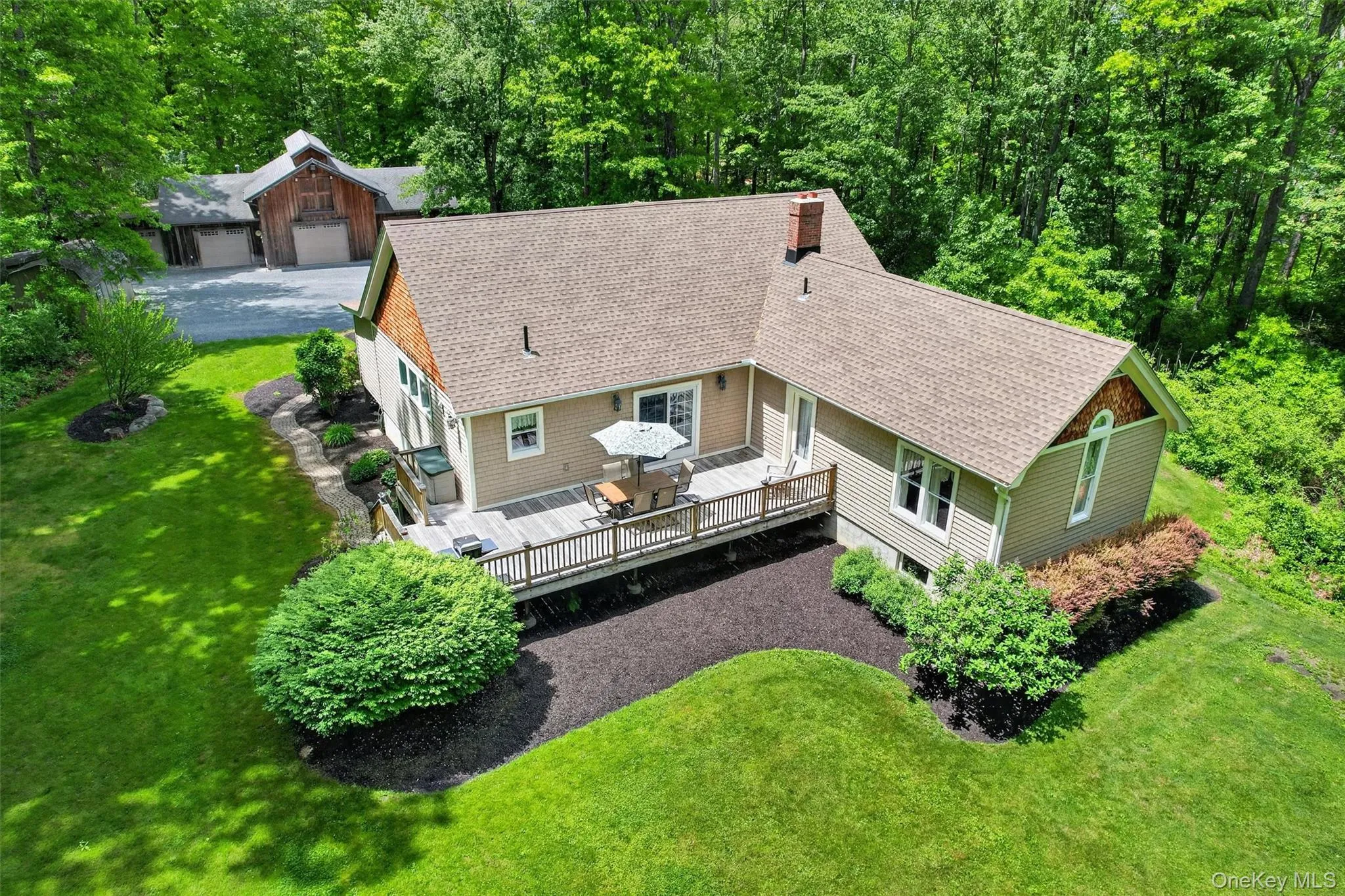 Expansive exterior featuring a wood deck, tan siding, and a shingle roof Expansive exterior featuring a wood deck, tan siding, and a shingle roof