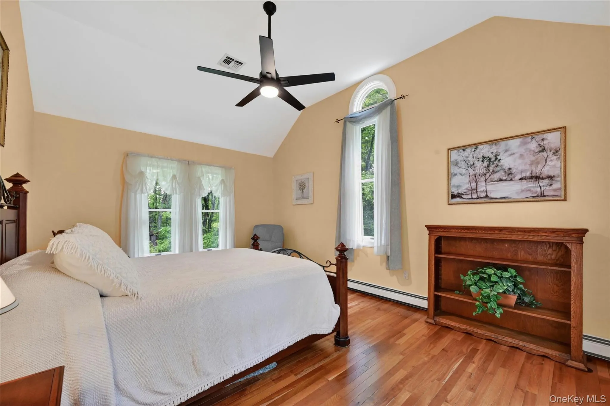 Vaulted ceiling with a contemporary ceiling fan, bright walls, wood-finish flooring, and multiple windows including an arched top window Vaulted ceiling with a contemporary ceiling fan, bright walls, wood-finish flooring, and multiple windows including an arched top window