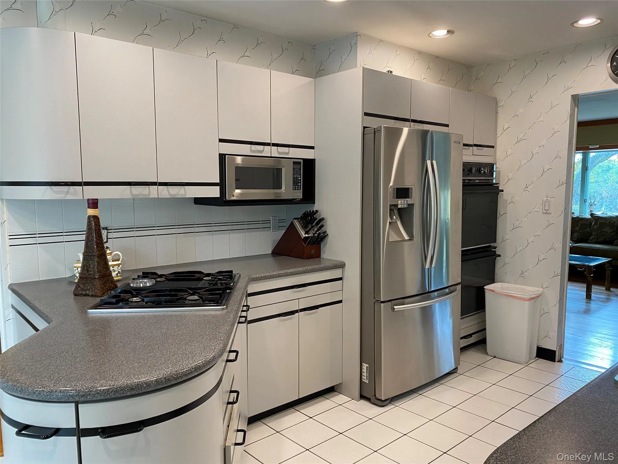 Kitchen featuring white cabinetry, light tile patterned floors, and stainless steel appliances Kitchen featuring white cabinetry, light tile patterned floors, and stainless steel appliances