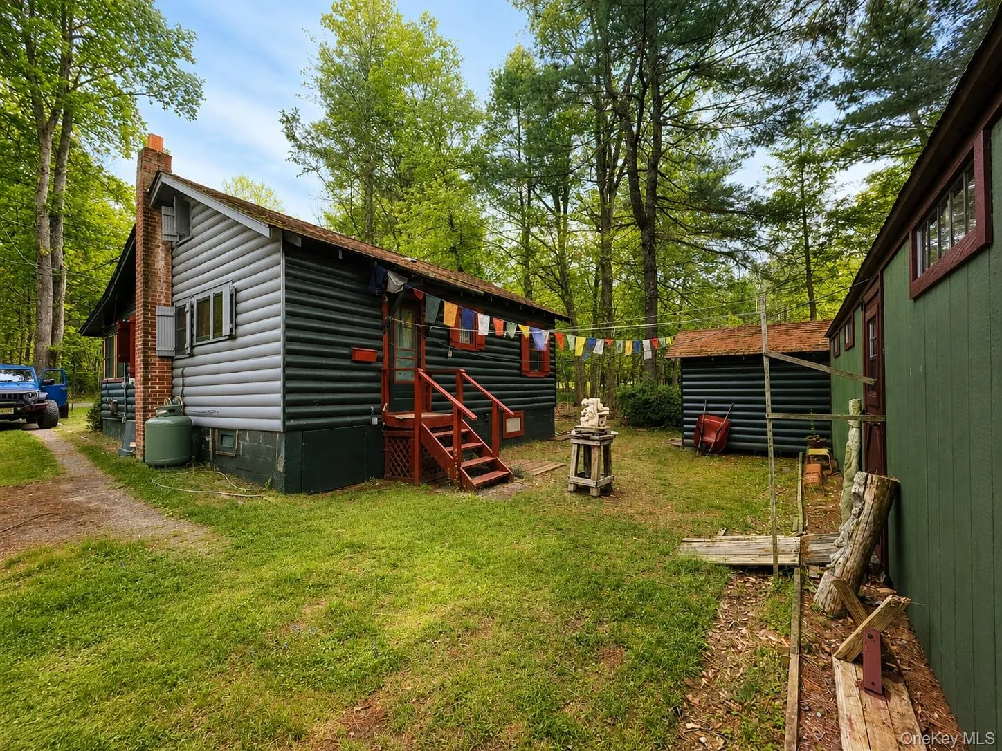 Wood-sided cabin featuring a brick chimney, red painted porch steps, and a metal roof Wood-sided cabin featuring a brick chimney, red painted porch steps, and a metal roof