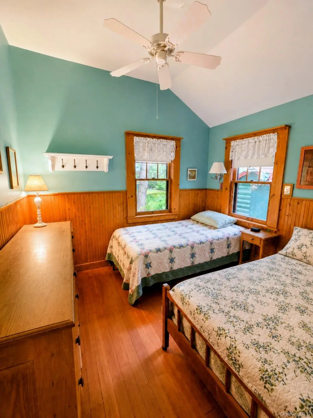 Vaulted ceiling with a ceiling fan, hardwood flooring, and wood paneling on lower walls Vaulted ceiling with a ceiling fan, hardwood flooring, and wood paneling on lower walls