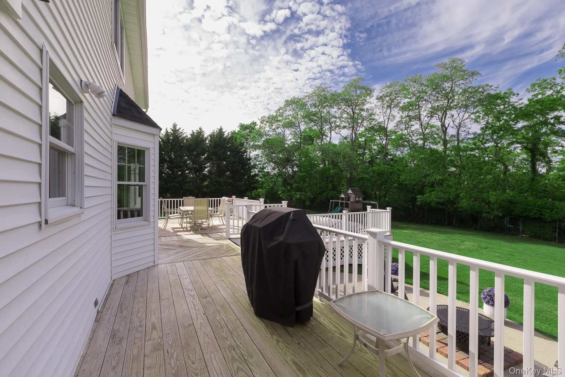 Expansive wood-finish deck with white railings, offering multiple areas for outdoor living Expansive wood-finish deck with white railings, offering multiple areas for outdoor living