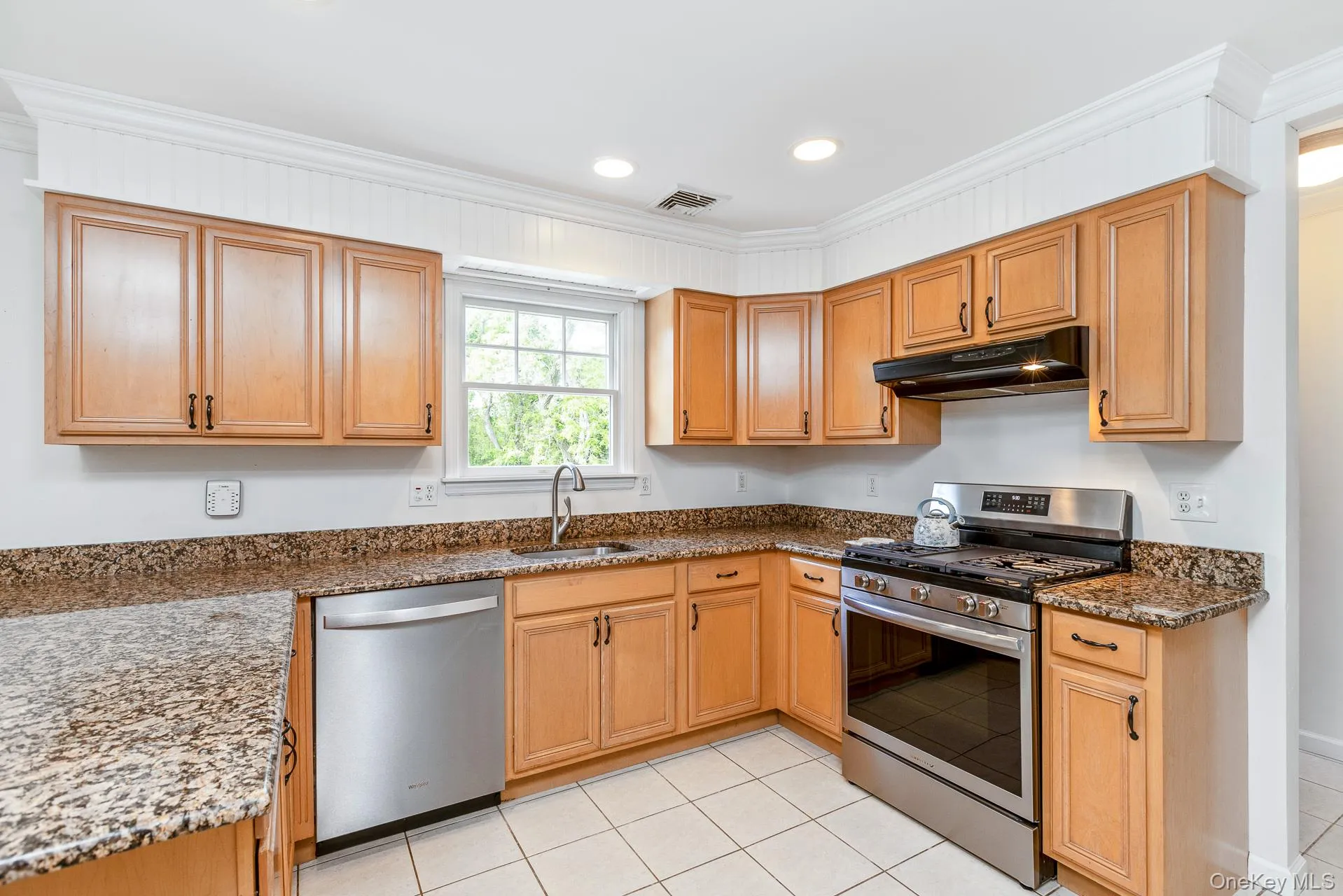 Kitchen featuring light wood cabinetry, granite-style countertops, and white tile flooring Kitchen featuring light wood cabinetry, granite-style countertops, and white tile flooring