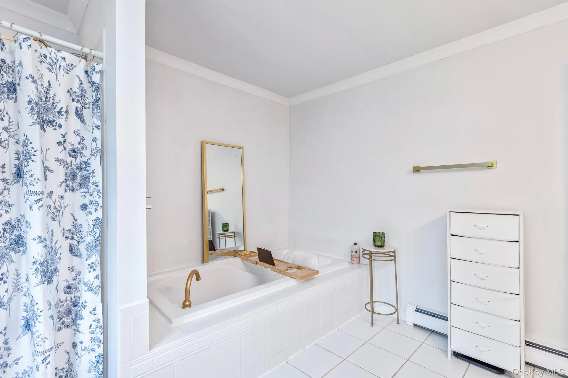 White tile flooring complements the recessed tub with brass fixtures White tile flooring complements the recessed tub with brass fixtures