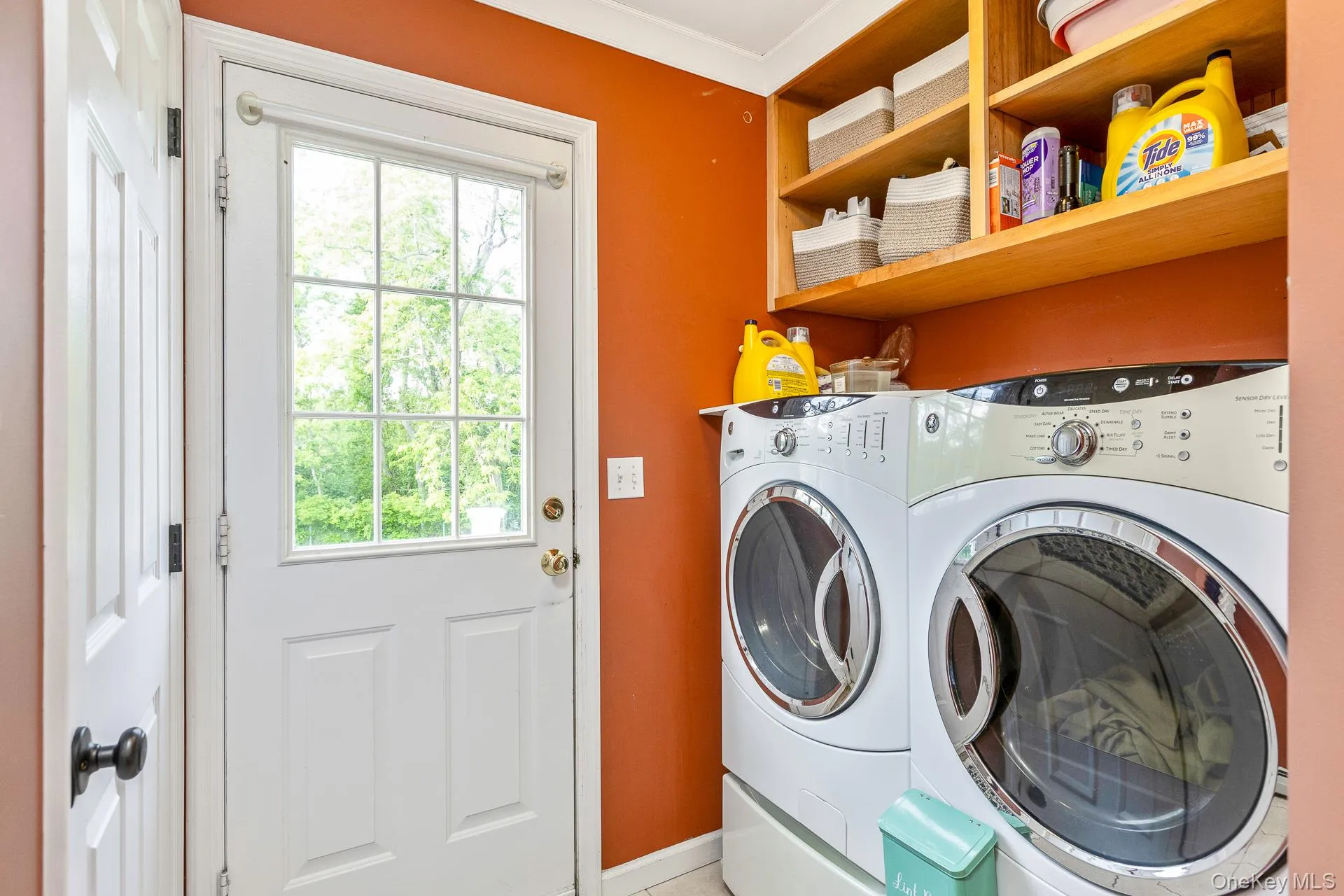 Functional utility area featuring a white paneled door with glass inserts, wood shelving, and a rich, warm wall color Functional utility area featuring a white paneled door with glass inserts, wood shelving, and a rich, warm wall color