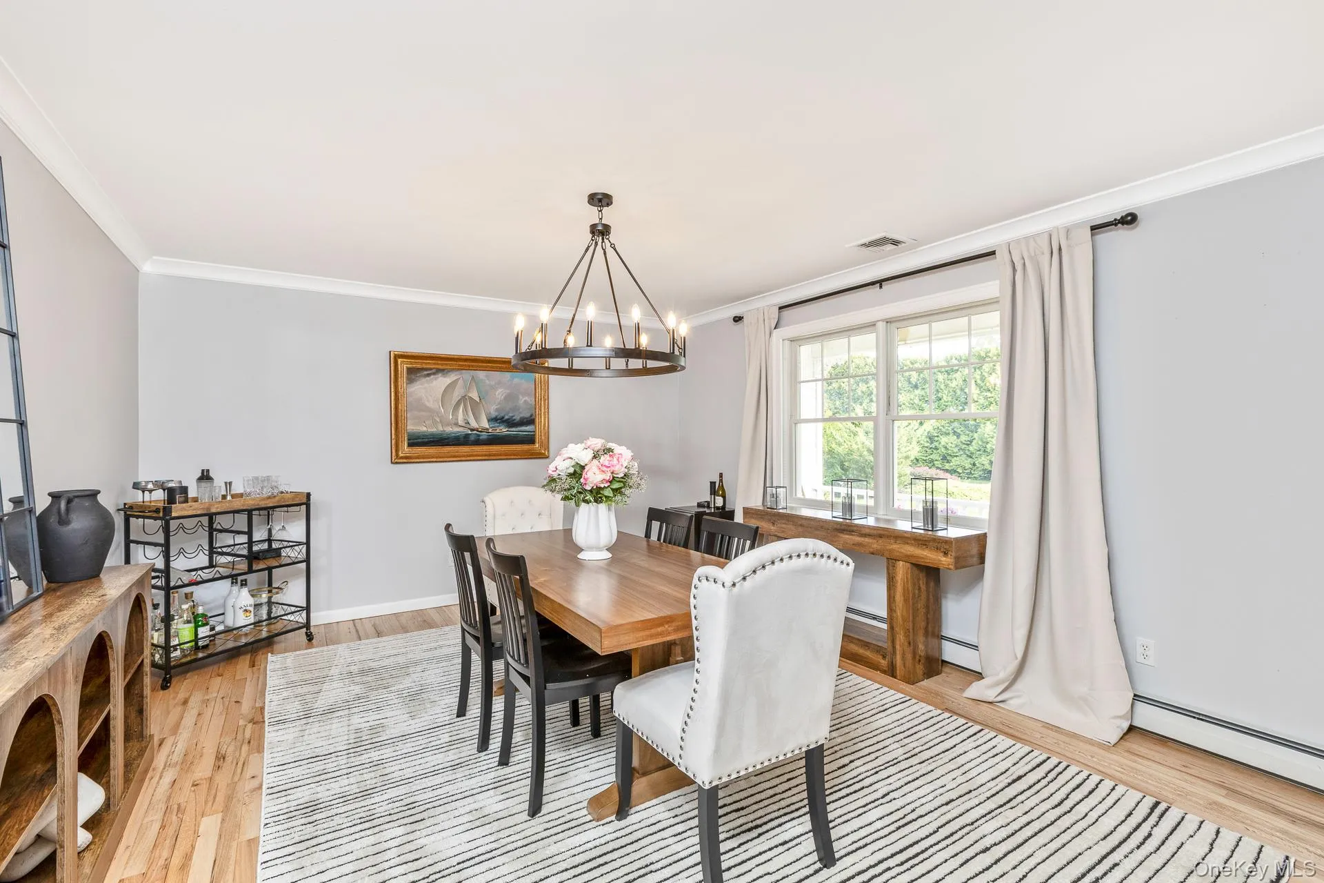 Dining room featuring wood-finish flooring, a large window, crown molding, and a chandelier Dining room featuring wood-finish flooring, a large window, crown molding, and a chandelier