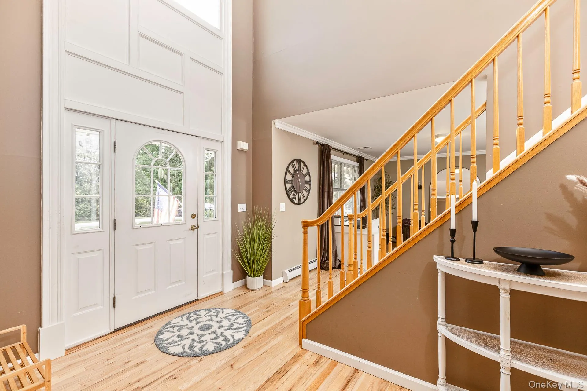 Two-story entry foyer featuring a transom window, sidelight windows, and light wood-finish flooring Two-story entry foyer featuring a transom window, sidelight windows, and light wood-finish flooring