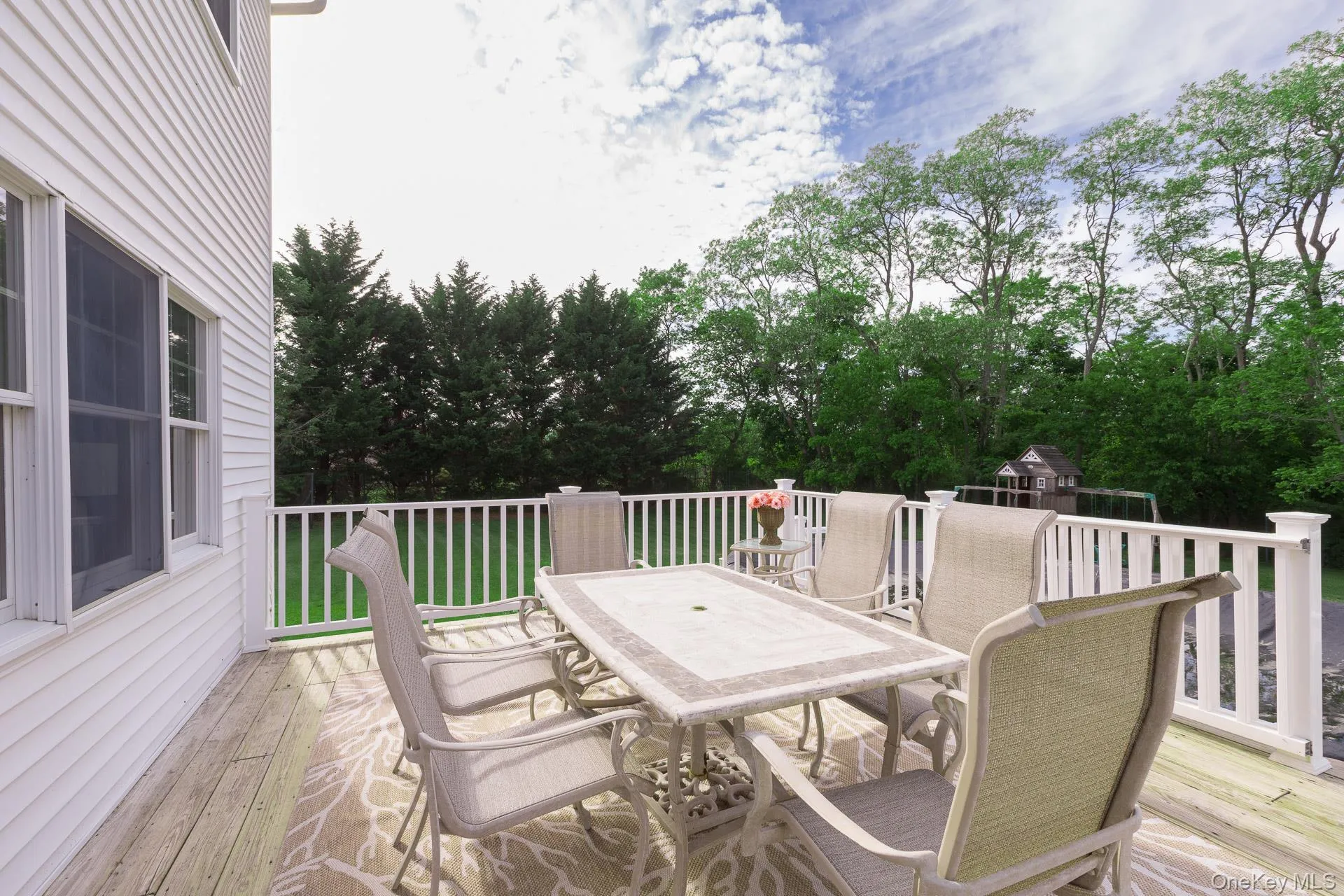 Expansive wood-finish deck with white railings, offering outdoor living space Expansive wood-finish deck with white railings, offering outdoor living space