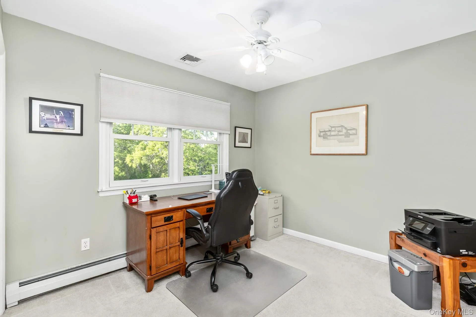 Bright room featuring light gray wall paint, a white ceiling fan with integrated lighting, a large window with roller shades, and light-toned carpeting Bright room featuring light gray wall paint, a white ceiling fan with integrated lighting, a large window with roller shades, and light-toned carpeting
