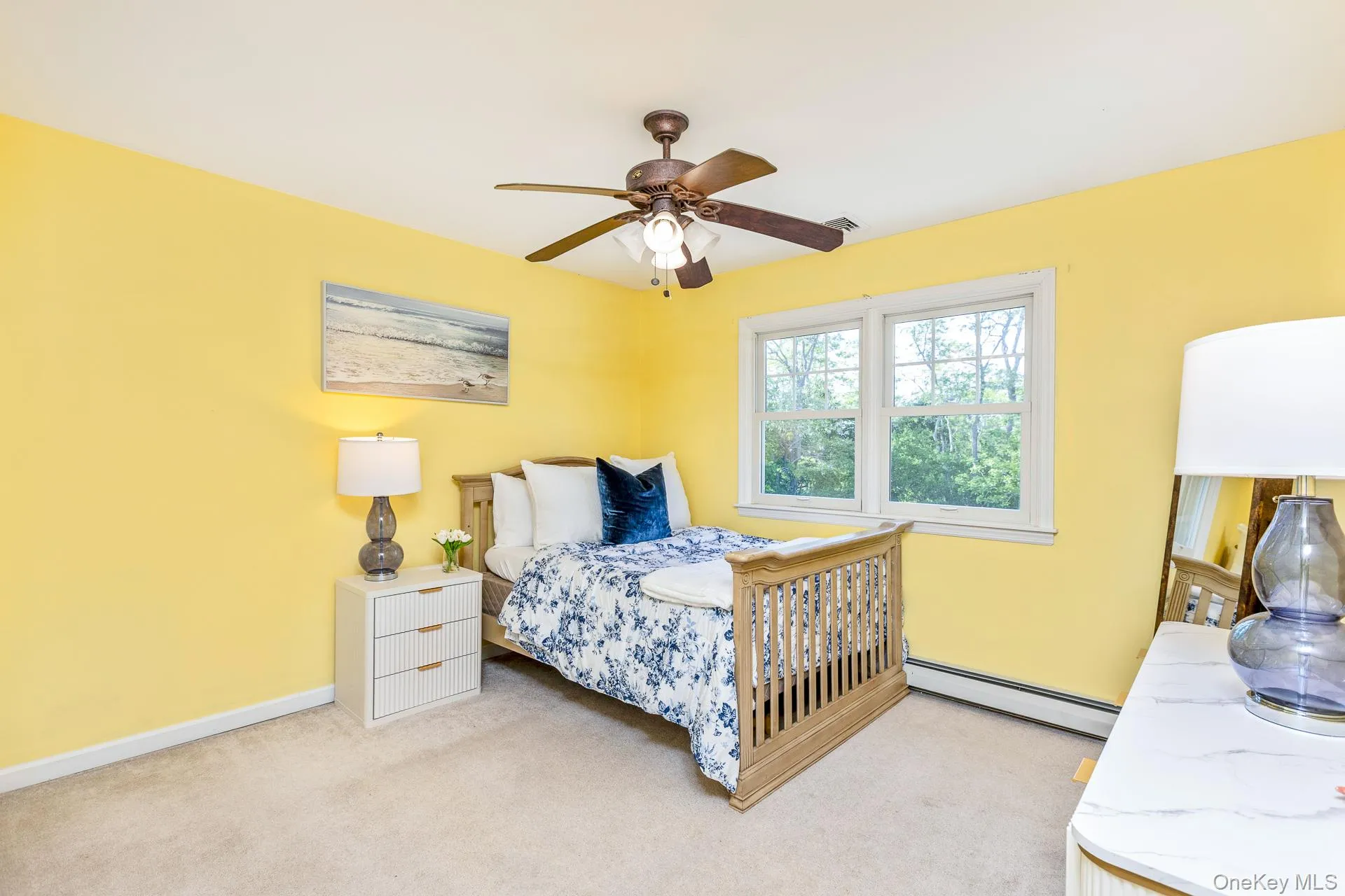 Carpeted interior room featuring a ceiling fan with light fixture, double-pane window, and light yellow painted walls Carpeted interior room featuring a ceiling fan with light fixture, double-pane window, and light yellow painted walls