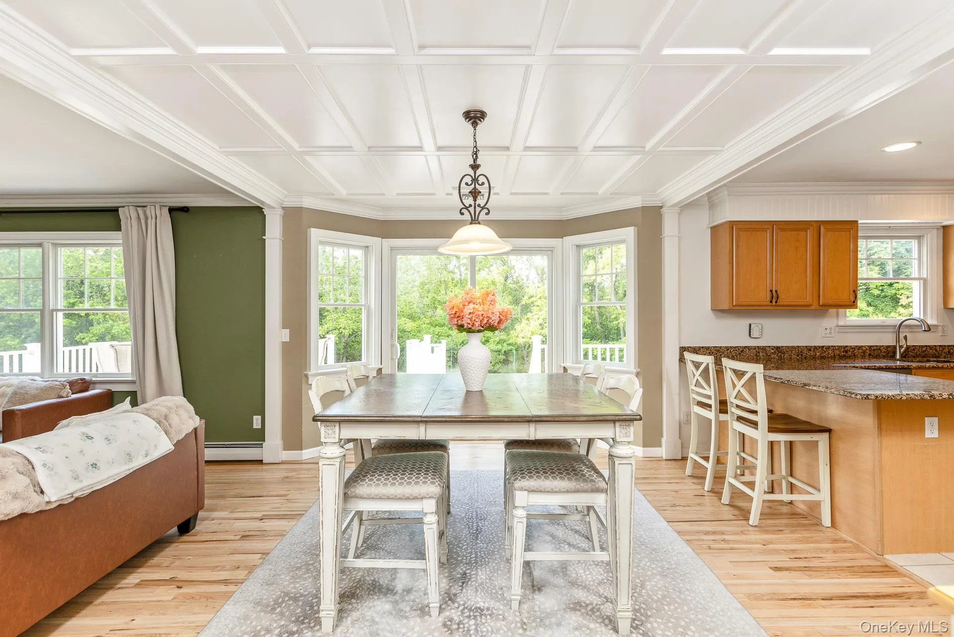 Bright dining area showcasing a stunning custom coffered ceiling, gleaming hardwood floors, and a sliding glass door that opens directly to the rear deck for seamless indoor-outdoor entertaining. Bright dining area showcasing a stunning custom coffered ceiling, gleaming hardwood floors, and a sliding glass door that opens directly to the rear deck for seamless indoor-outdoor entertaining.