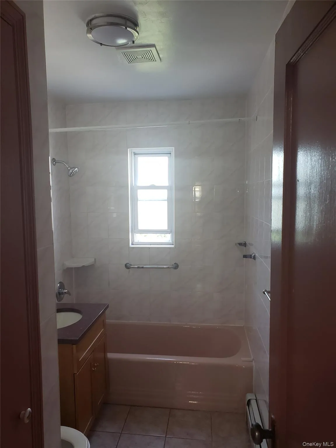 Bathroom with shower combination, visible vents, baseboard heating, tile patterned flooring, and vanity Bathroom with shower combination, visible vents, baseboard heating, tile patterned flooring, and vanity