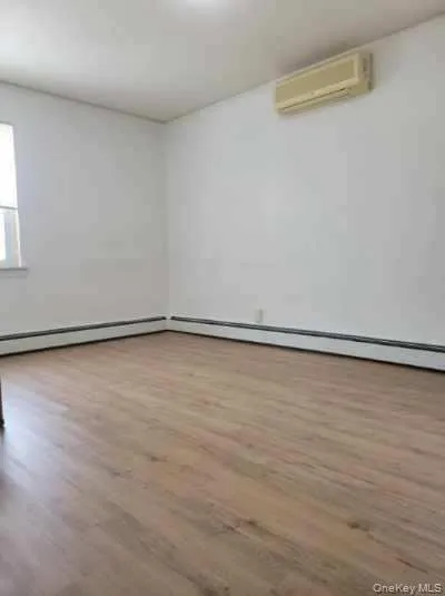 Unfurnished room with wood finished floors and a wall mounted air conditioner Unfurnished room with wood finished floors and a wall mounted air conditioner