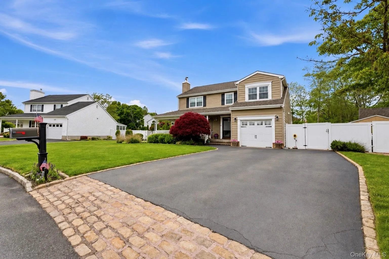 Two-story home with light brown siding, white trim, and a prominent attached garage Two-story home with light brown siding, white trim, and a prominent attached garage