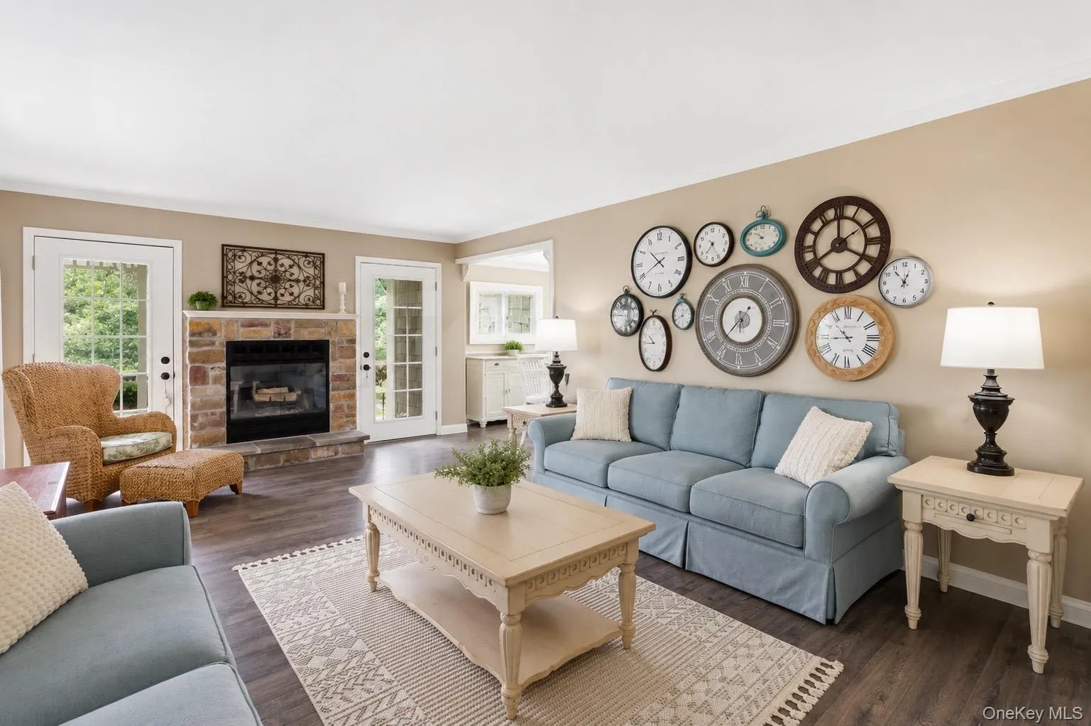 Living area featuring a stone fireplace with hearth, dark wood-finish flooring, and two sets of glass-paned double doors Living area featuring a stone fireplace with hearth, dark wood-finish flooring, and two sets of glass-paned double doors