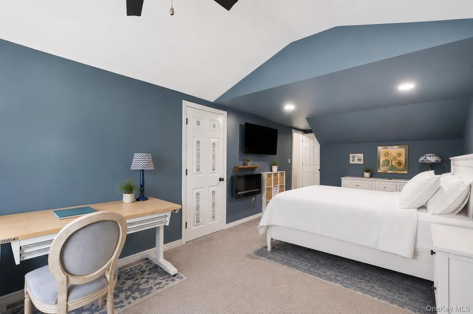 Carpeted room with a blue accent wall and a vaulted ceiling Carpeted room with a blue accent wall and a vaulted ceiling