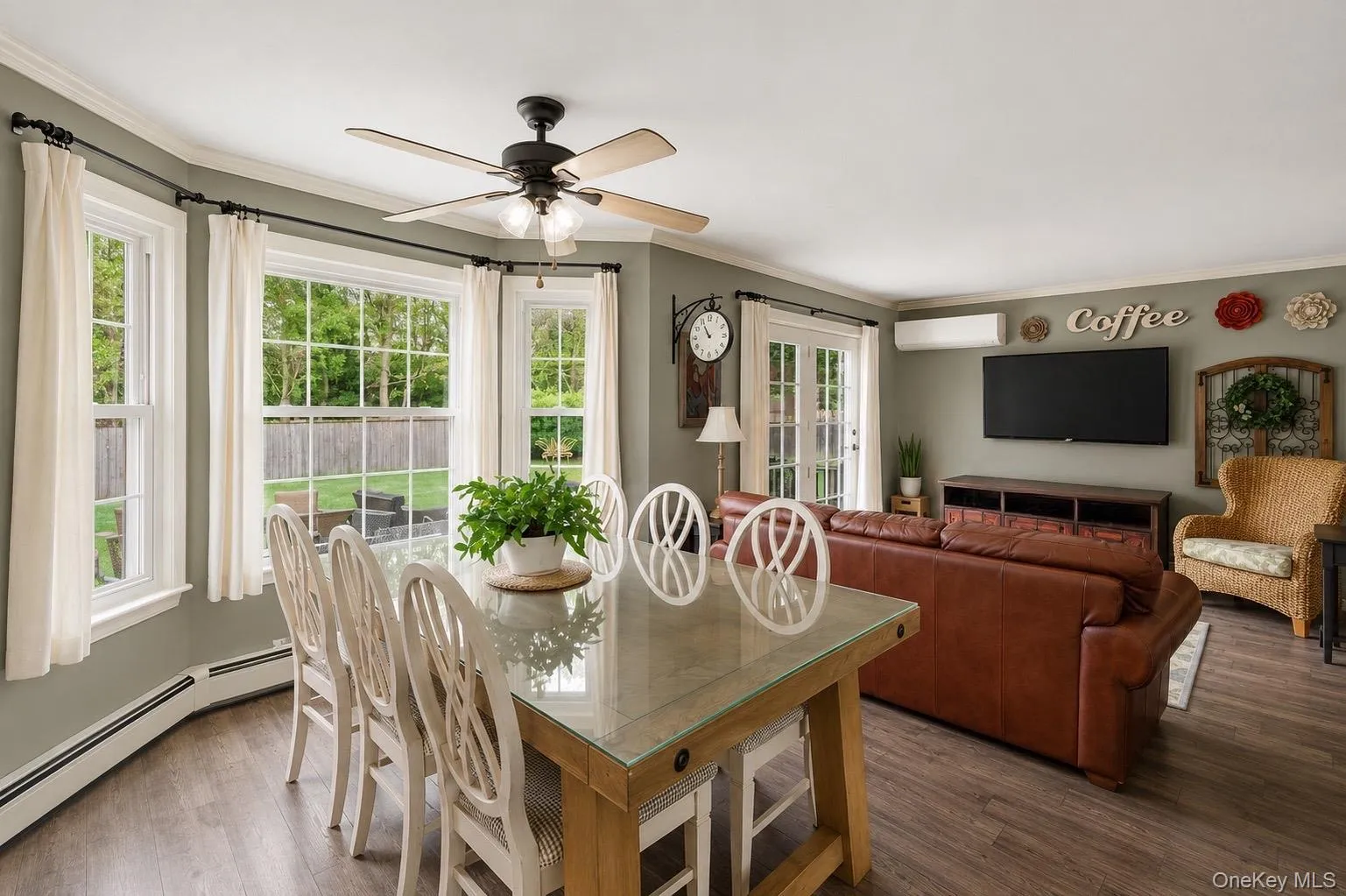 Dining area featuring wood-finish flooring, a bay window with multiple panes, a ceiling fan with integrated lighting, and crown molding Dining area featuring wood-finish flooring, a bay window with multiple panes, a ceiling fan with integrated lighting, and crown molding