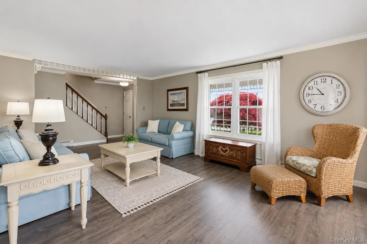 Spacious living area featuring wood-finish flooring, a large window, and crown molding Spacious living area featuring wood-finish flooring, a large window, and crown molding
