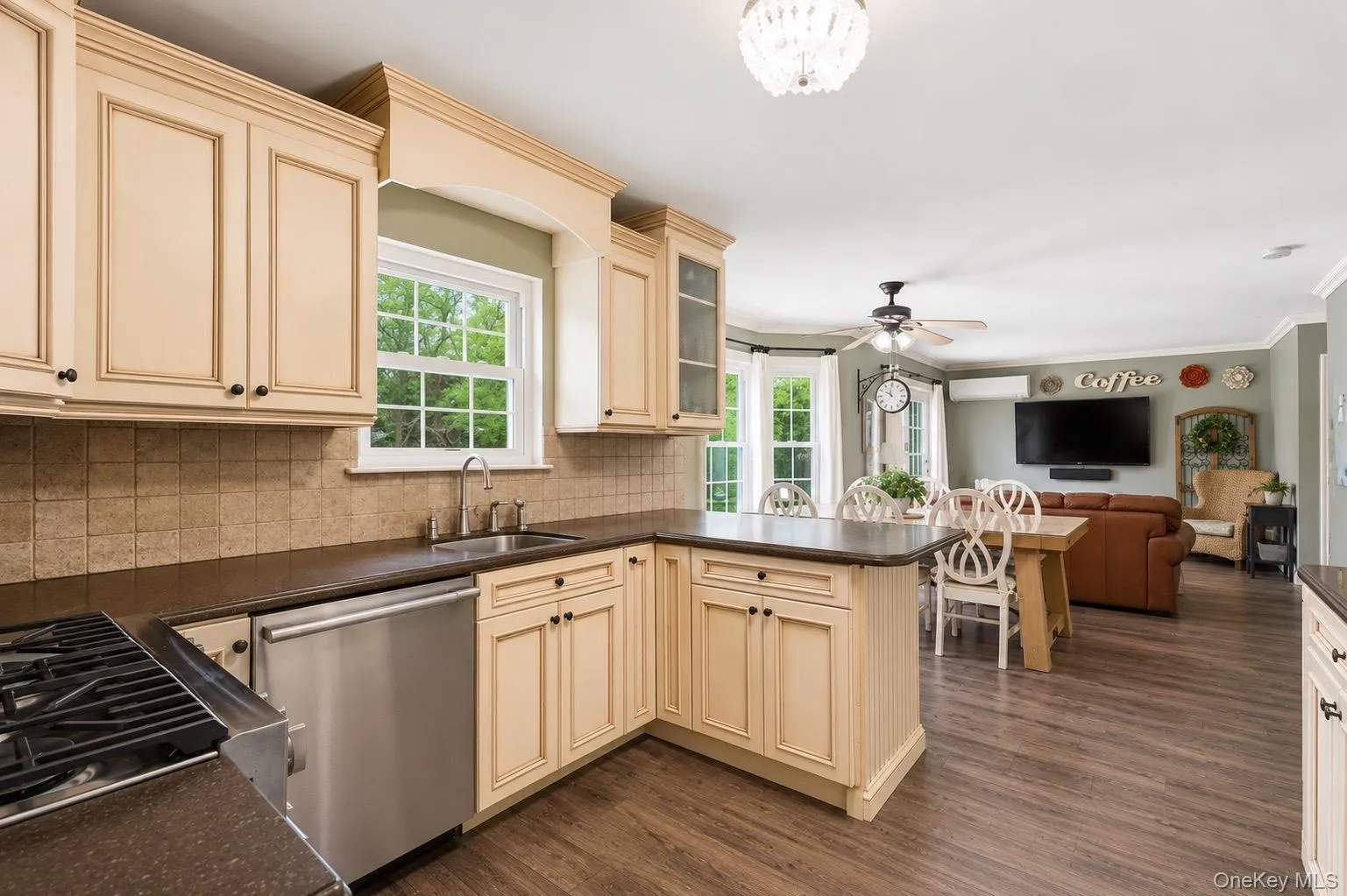 Kitchen featuring cream-toned cabinetry with dark hardware, dark countertops, a tiled backsplash, and stainless steel appliances Kitchen featuring cream-toned cabinetry with dark hardware, dark countertops, a tiled backsplash, and stainless steel appliances