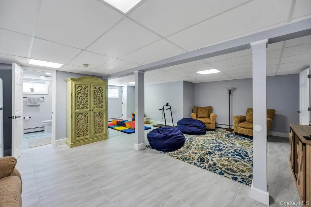 Finished lower level featuring recessed lighting, light gray wall paint, light-toned tile flooring, and a full bathroom with a window Finished lower level featuring recessed lighting, light gray wall paint, light-toned tile flooring, and a full bathroom with a window
