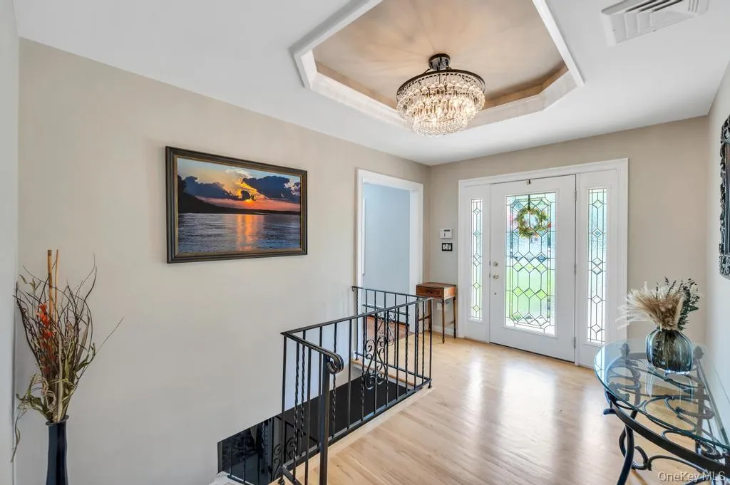 Entryway featuring wood-finish flooring, a decorative glass paneled front door, and a coffered ceiling with a chandelier Entryway featuring wood-finish flooring, a decorative glass paneled front door, and a coffered ceiling with a chandelier