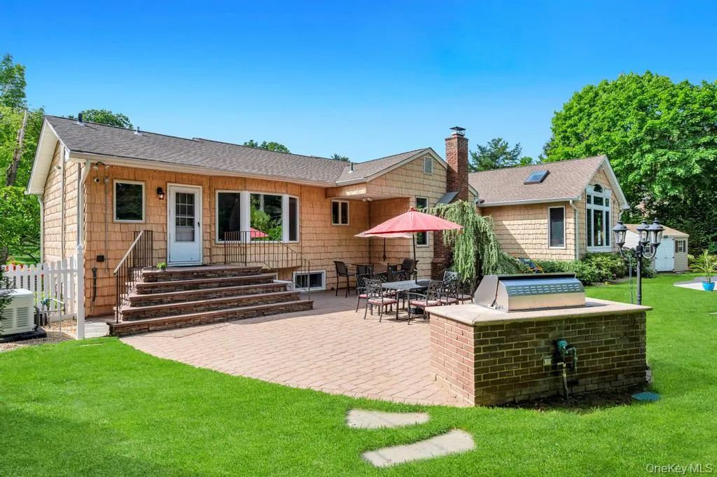 Expansive paver patio with a built-in brick grilling station, complemented by a large green lawn Expansive paver patio with a built-in brick grilling station, complemented by a large green lawn