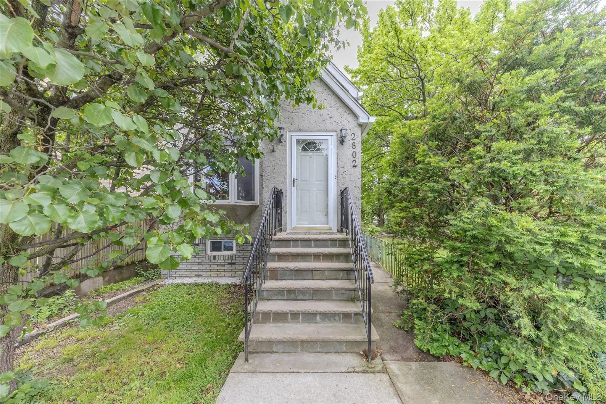 Stucco exterior featuring a prominent entryway with a white paneled door and decorative glass insert Stucco exterior featuring a prominent entryway with a white paneled door and decorative glass insert