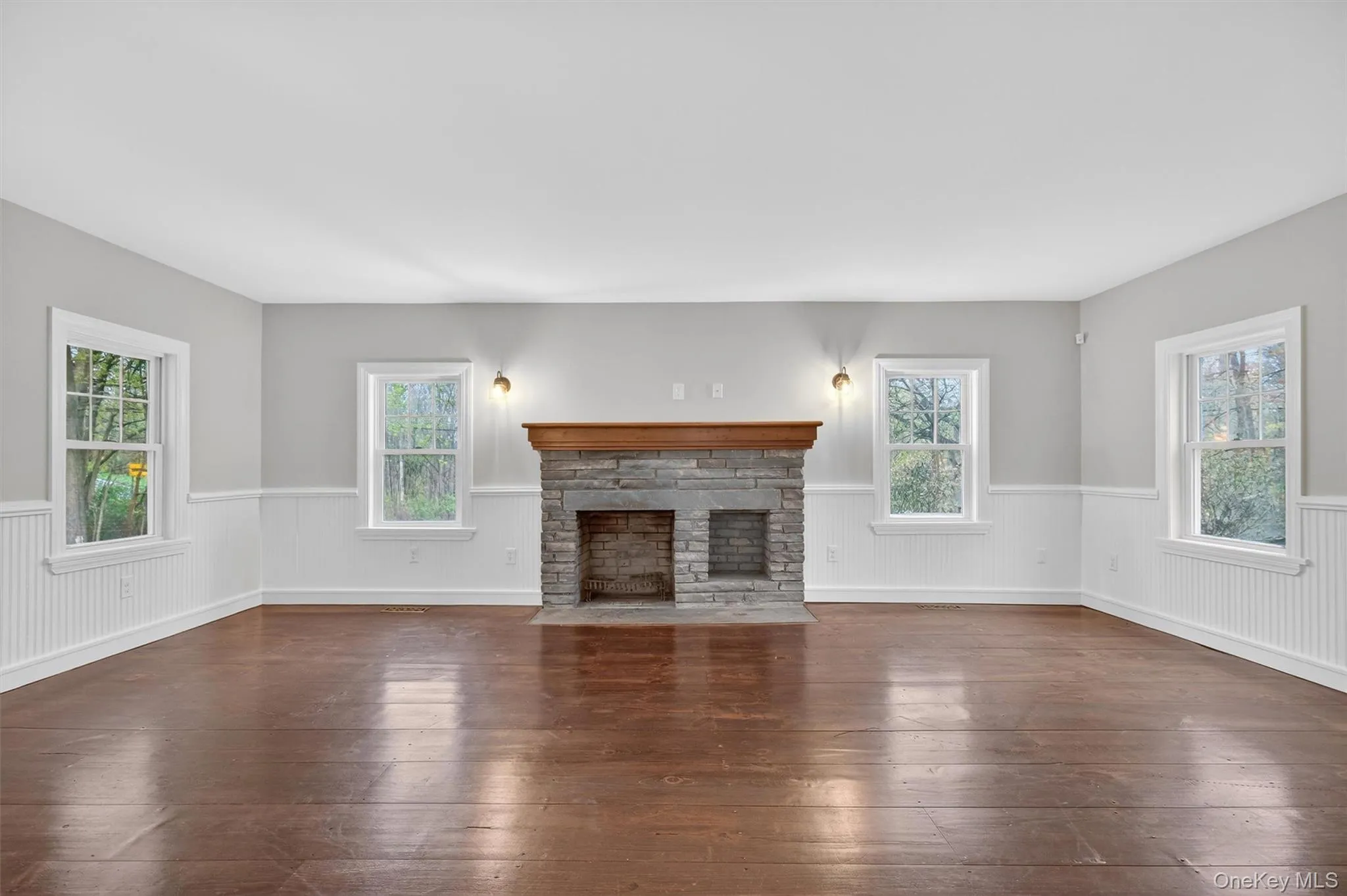 Formal living room with decorative stone fireplace, hardwood floors, and beadboard wainscoting. Formal living room with decorative stone fireplace, hardwood floors, and beadboard wainscoting.