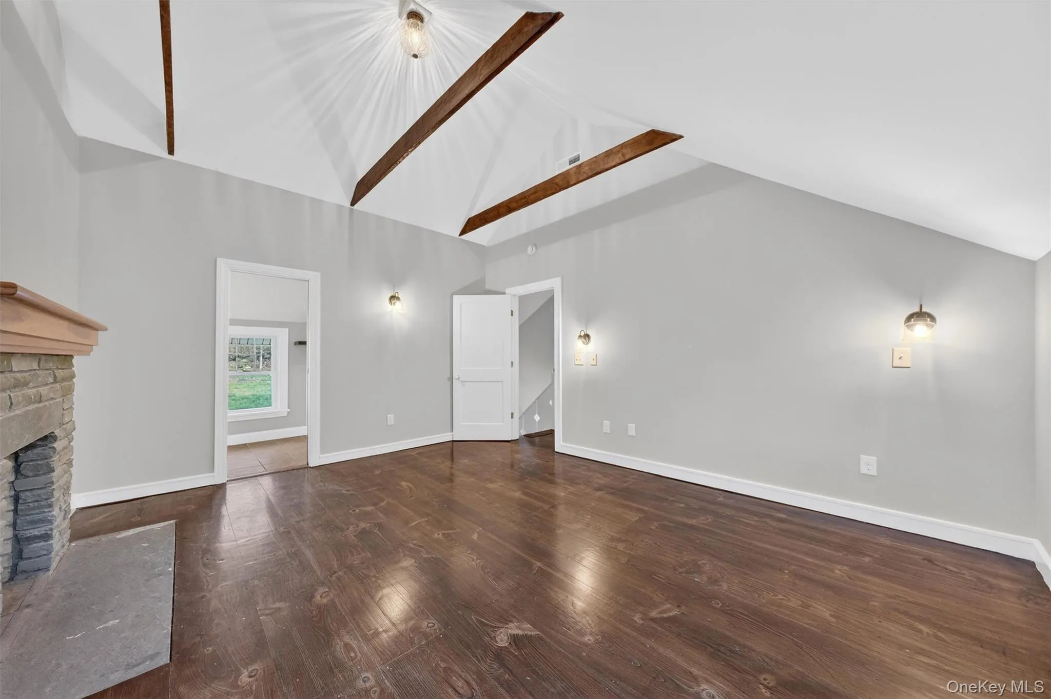 Primary bedroom with exposed beams, hardwood floors, decorative fireplace, and en-suite bathroom. Primary bedroom with exposed beams, hardwood floors, decorative fireplace, and en-suite bathroom.