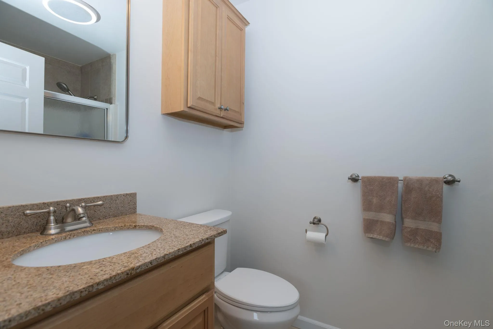 Bathroom featuring a wood-finish vanity with a granite countertop, undermount sink, and brushed nickel faucet Bathroom featuring a wood-finish vanity with a granite countertop, undermount sink, and brushed nickel faucet