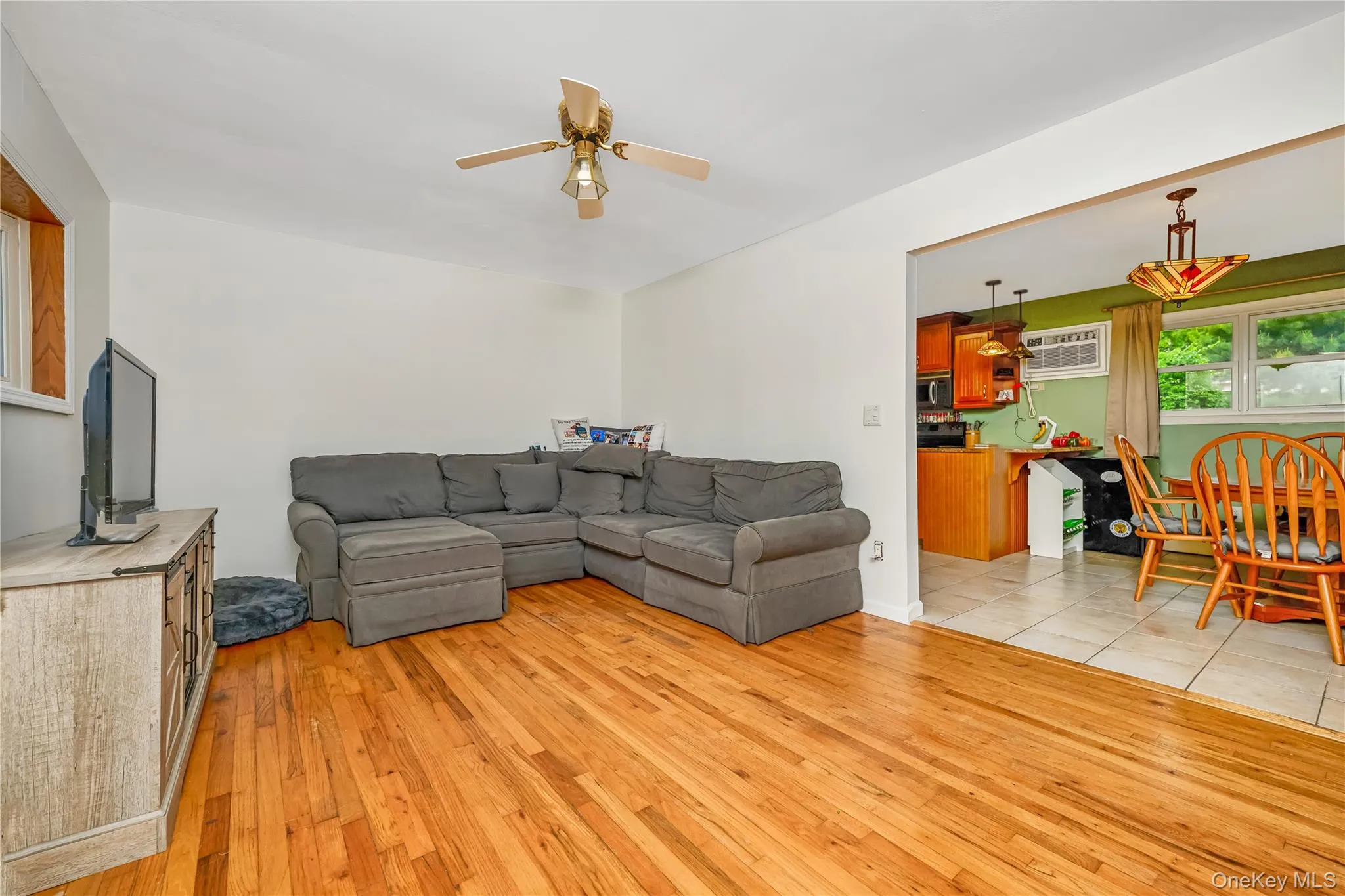 Living area featuring wood-finish flooring and a ceiling fan with integrated lighting Living area featuring wood-finish flooring and a ceiling fan with integrated lighting
