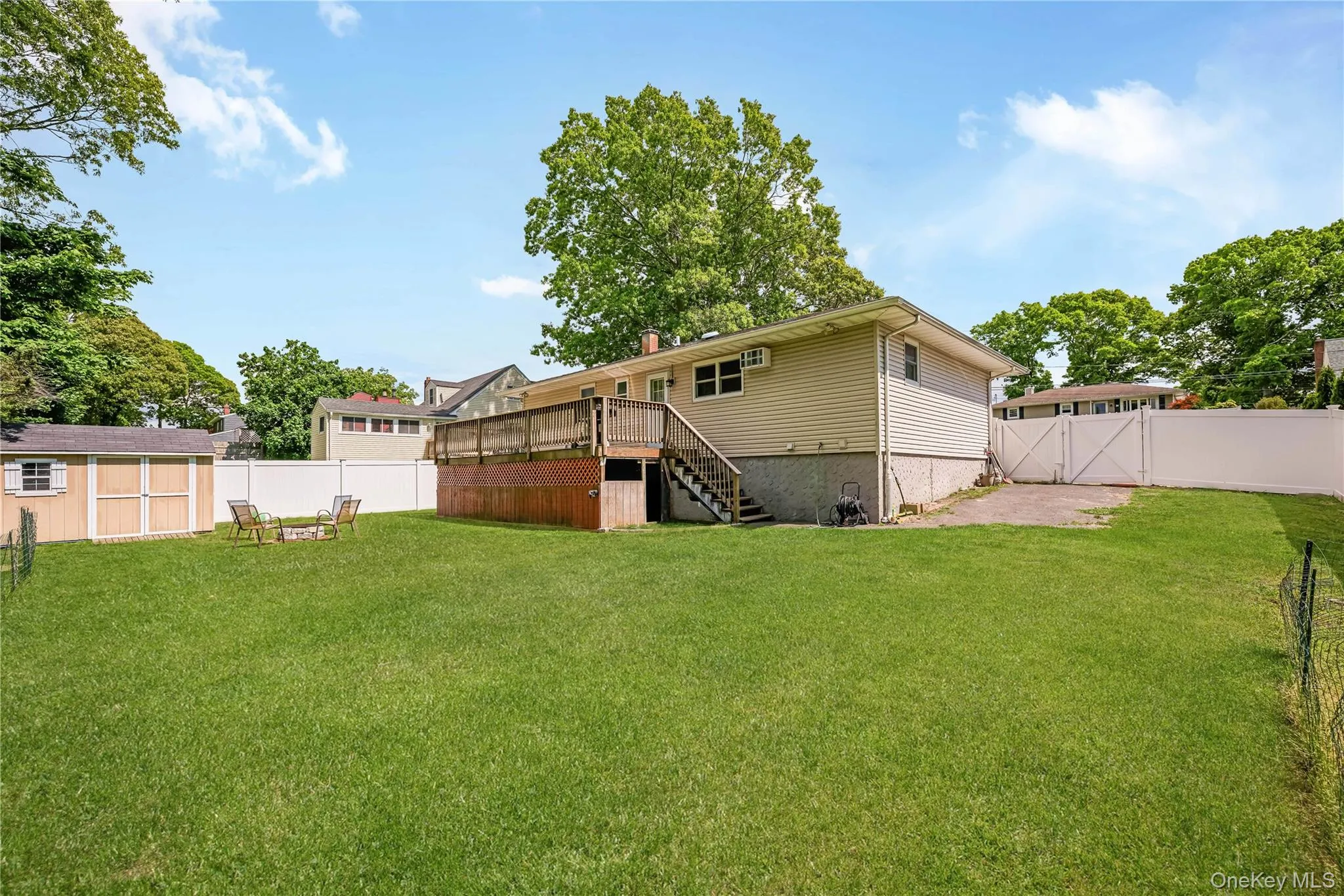 Expansive backyard featuring a large green lawn, a multi-level wood deck with stairs, and a detached storage shed Expansive backyard featuring a large green lawn, a multi-level wood deck with stairs, and a detached storage shed